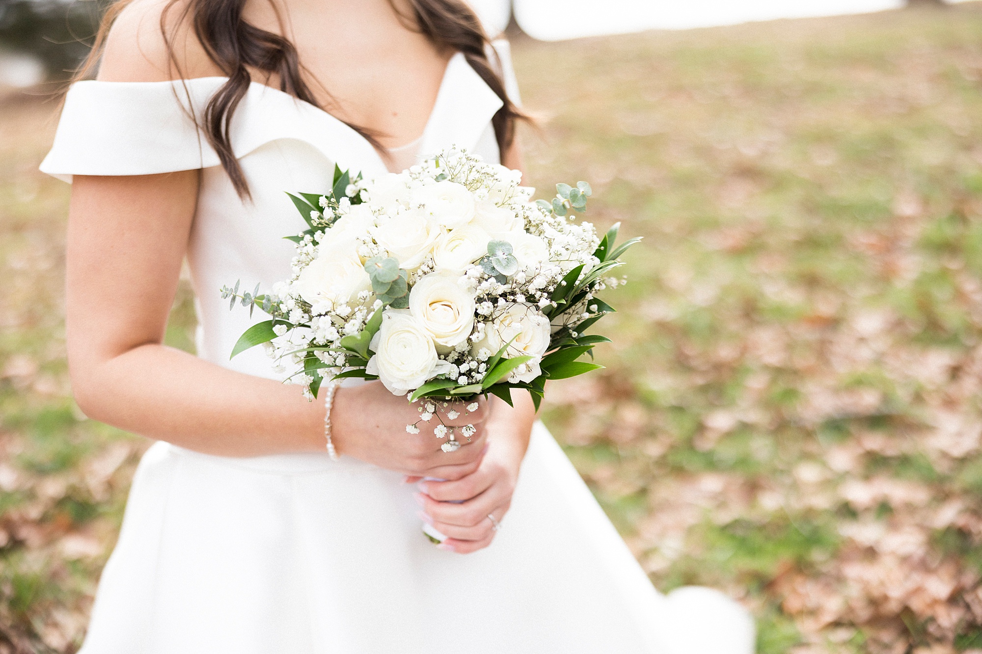 bride holds bouquet f white flowers with baby's breath