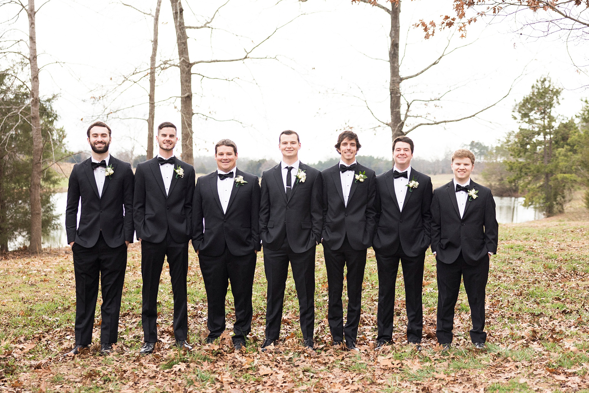 groom poses with groomsmen in tuxes