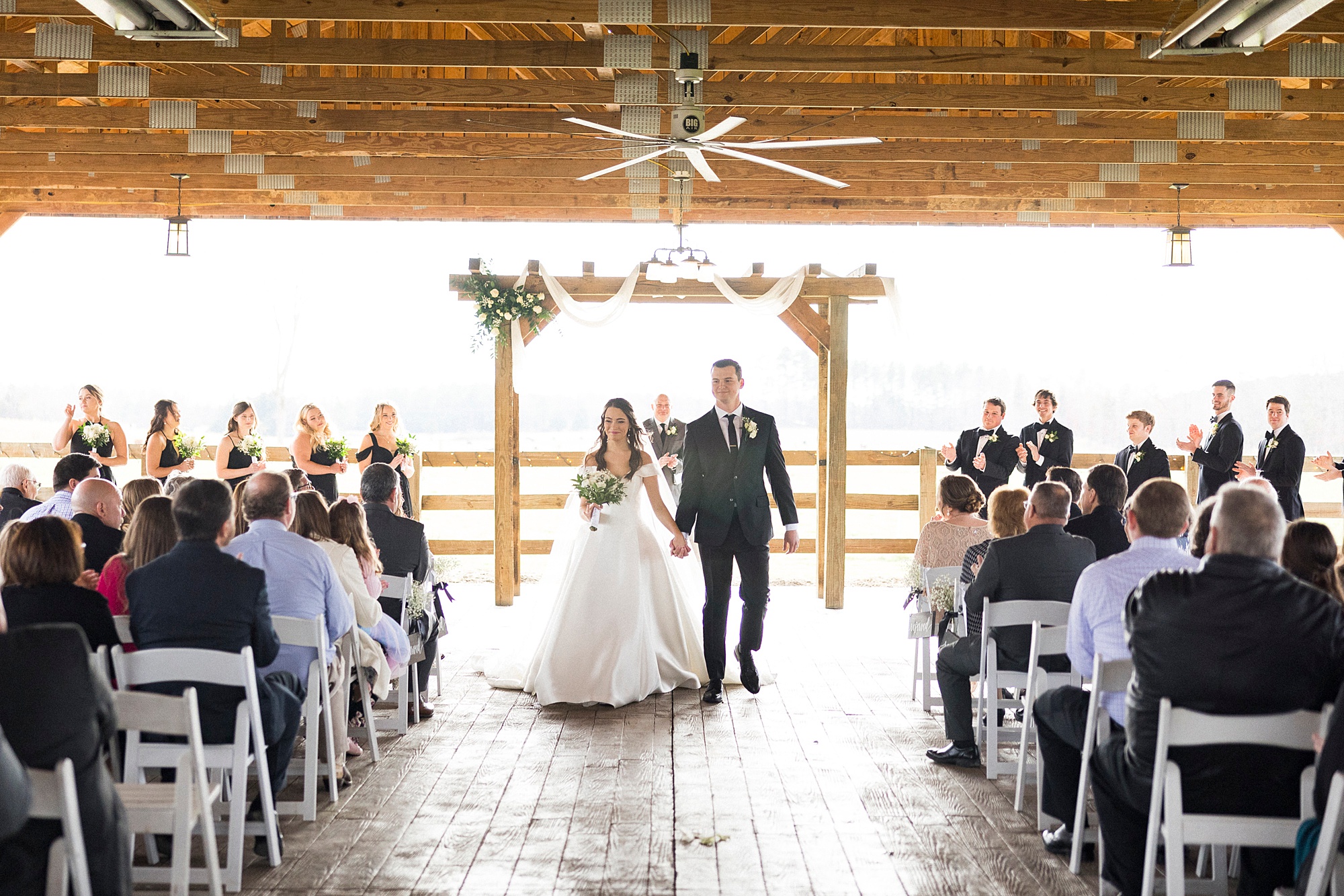 bride and groom hold hands walking up aisle after Christ-centered ceremony at The Farm at Brusharbor