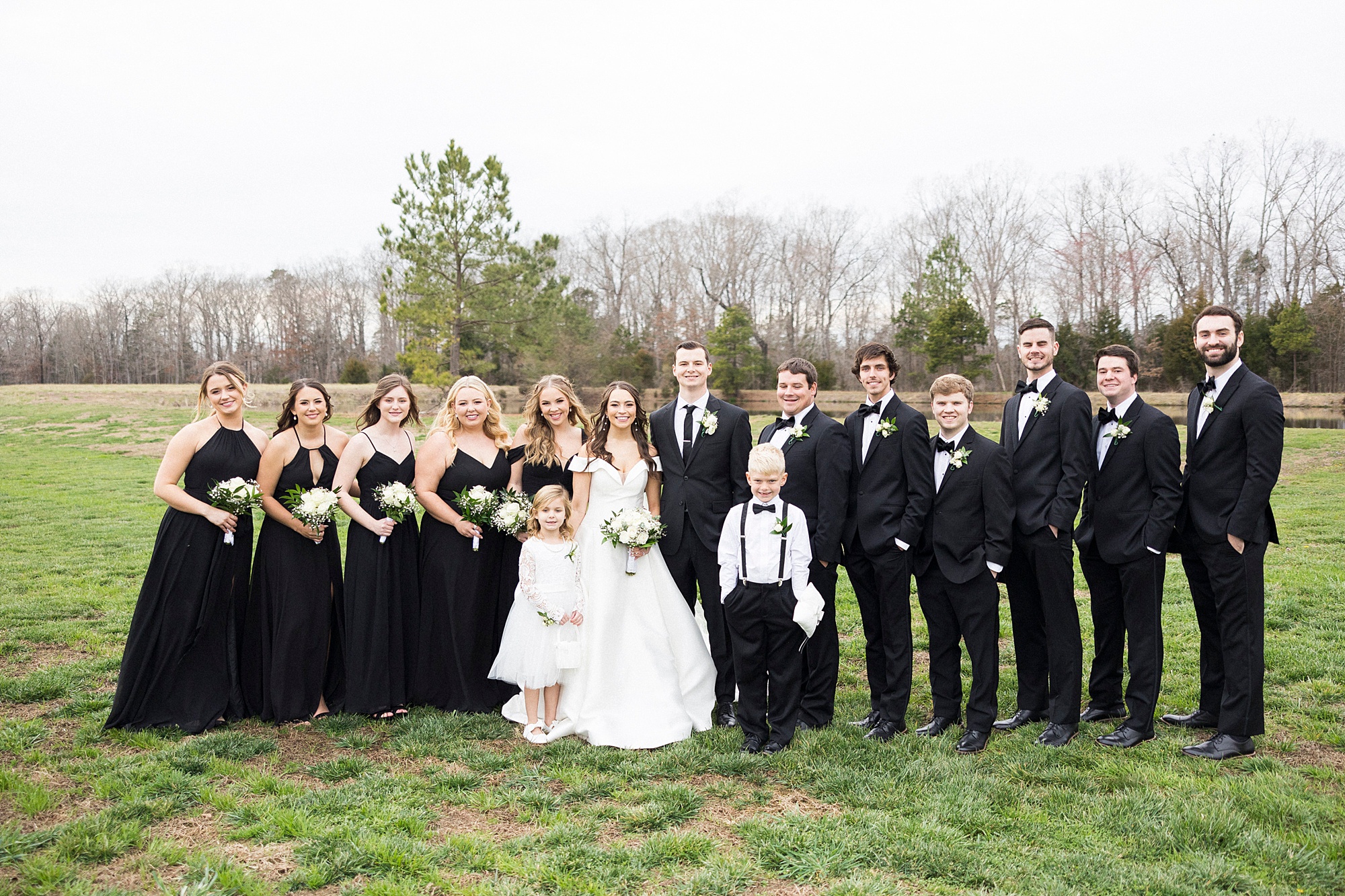 bride and groom pose with wedding party, ring bearer, and flower girl