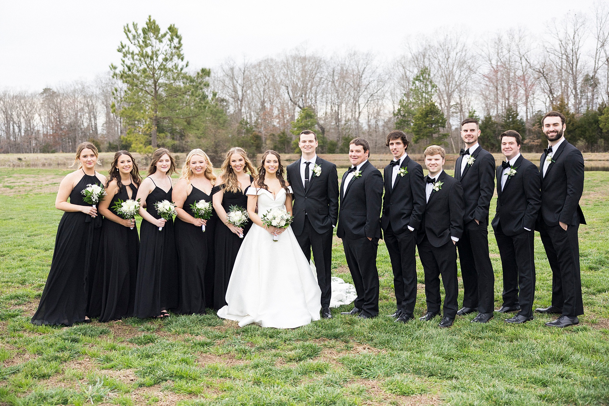 newlyweds pose with wedding party in all black attire