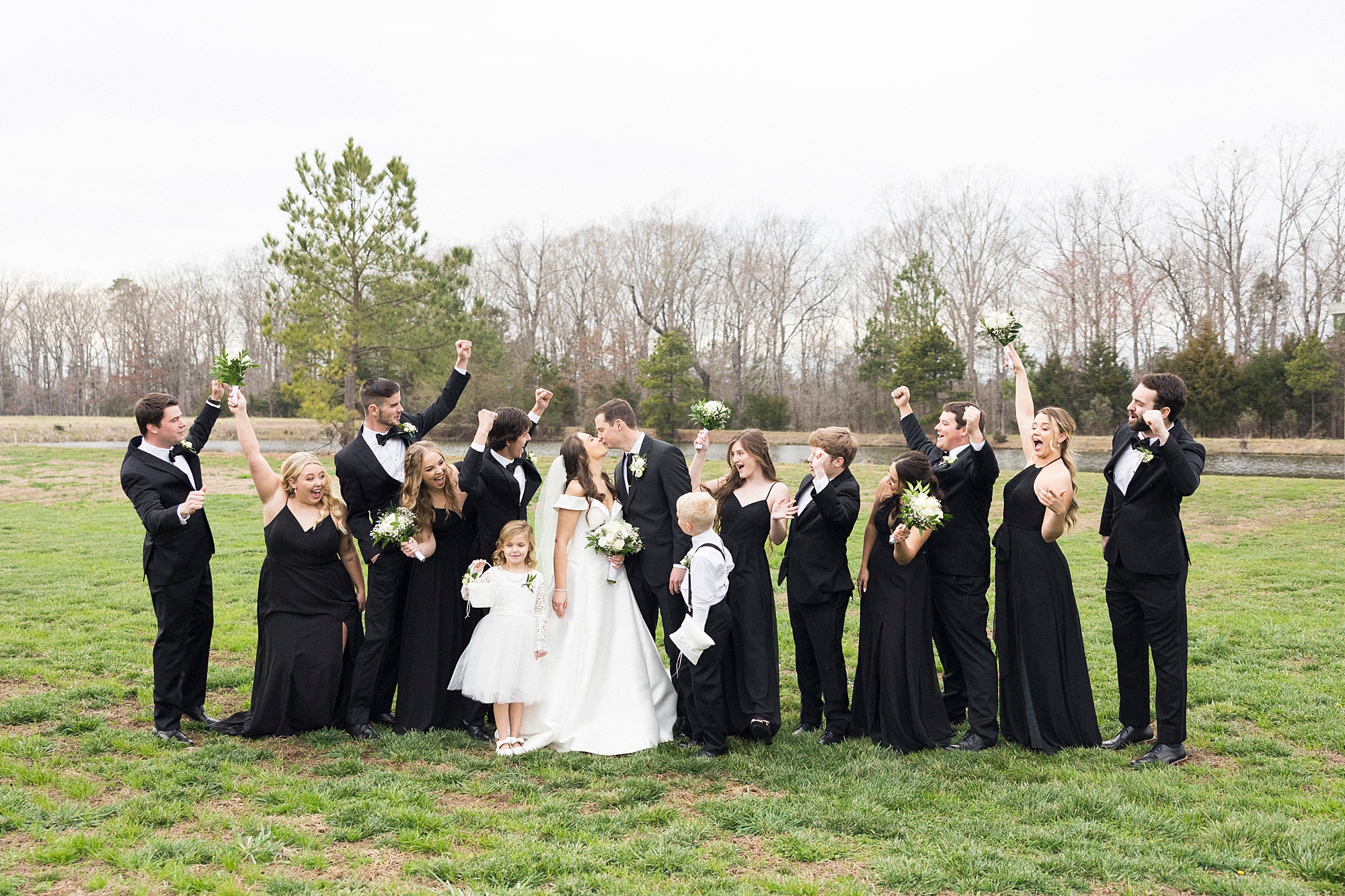 newlyweds kiss while wedding party in all-black cheers