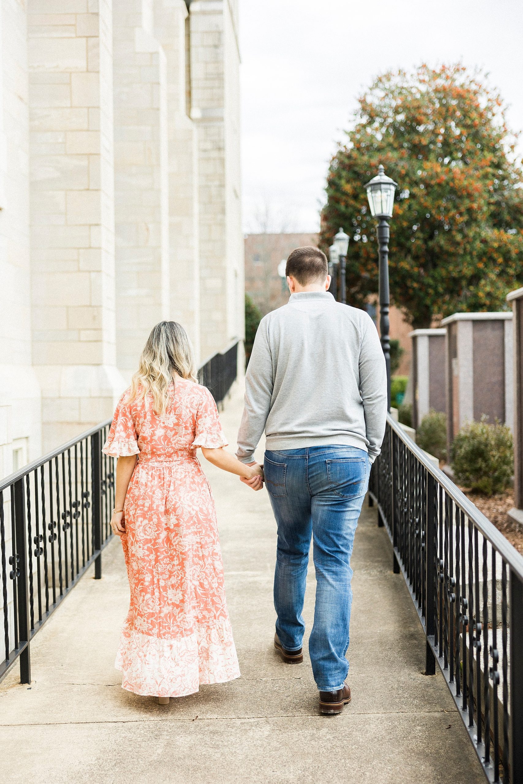 engaged couple walks beside old church