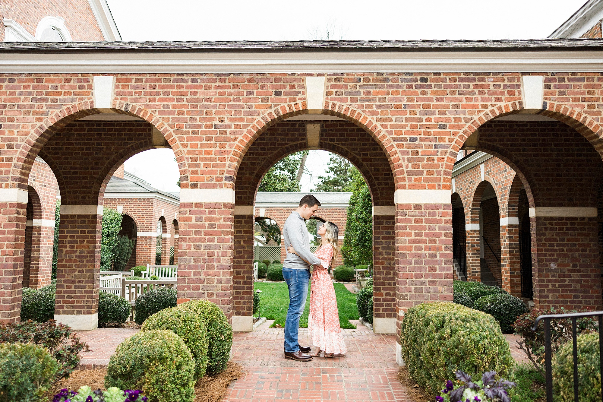 bride and groom pose under brick archway during Downtown Concord engagement session