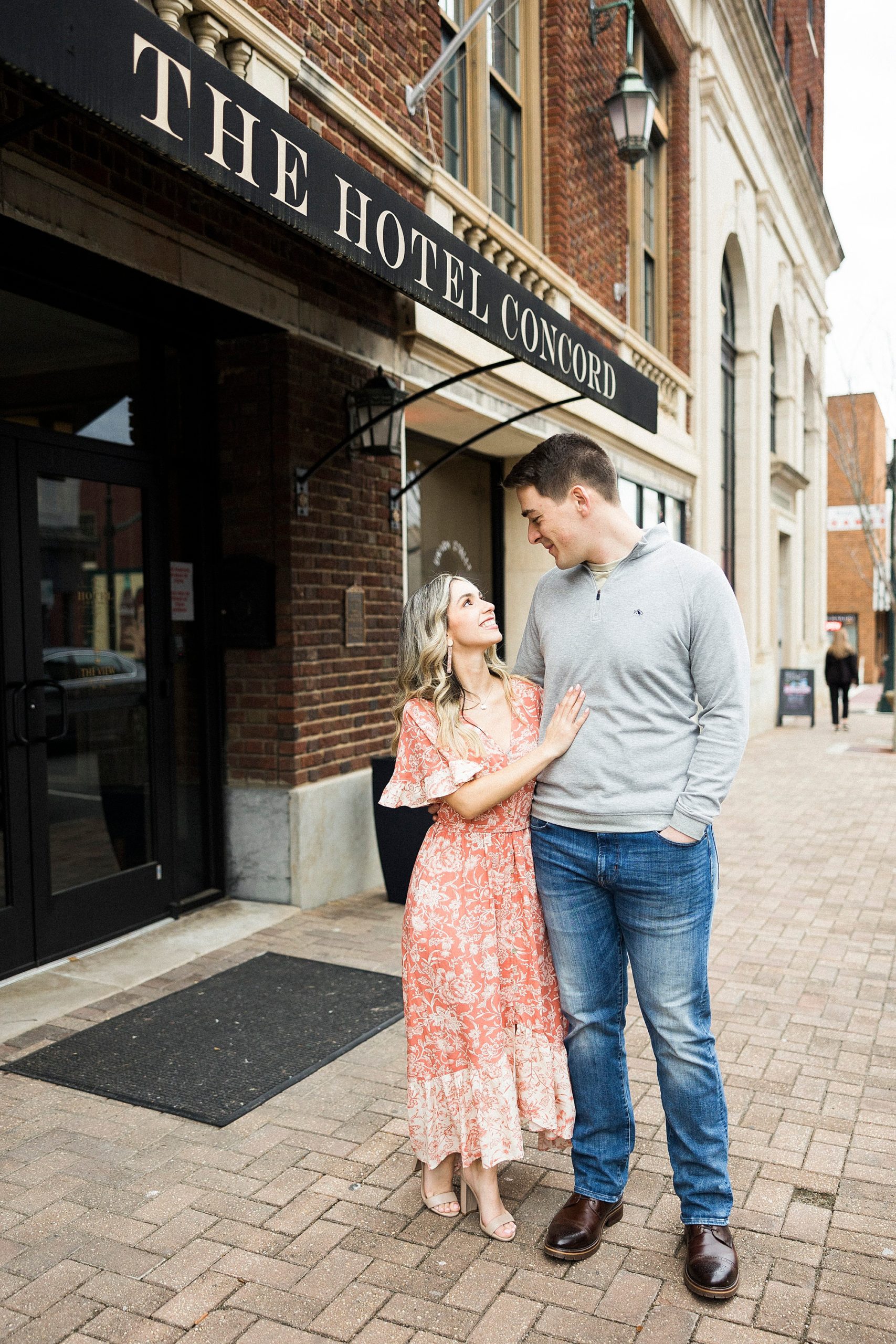 bride and groom smile at each other walking down streets during Downtown Concord engagement session