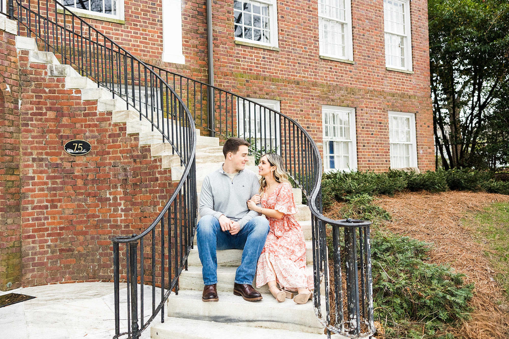 couple poses on winding staircase together during Downtown Concord engagement session