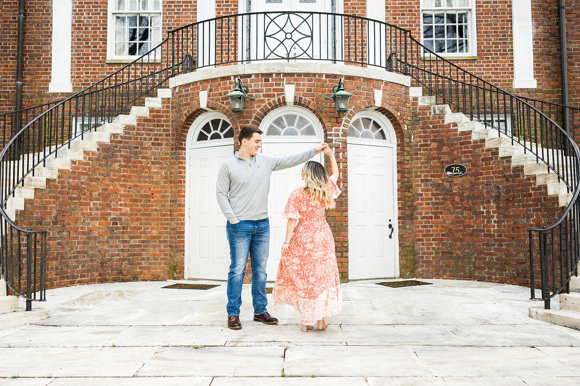 groom twirls bride in front of brick building during Downtown Concord engagement session