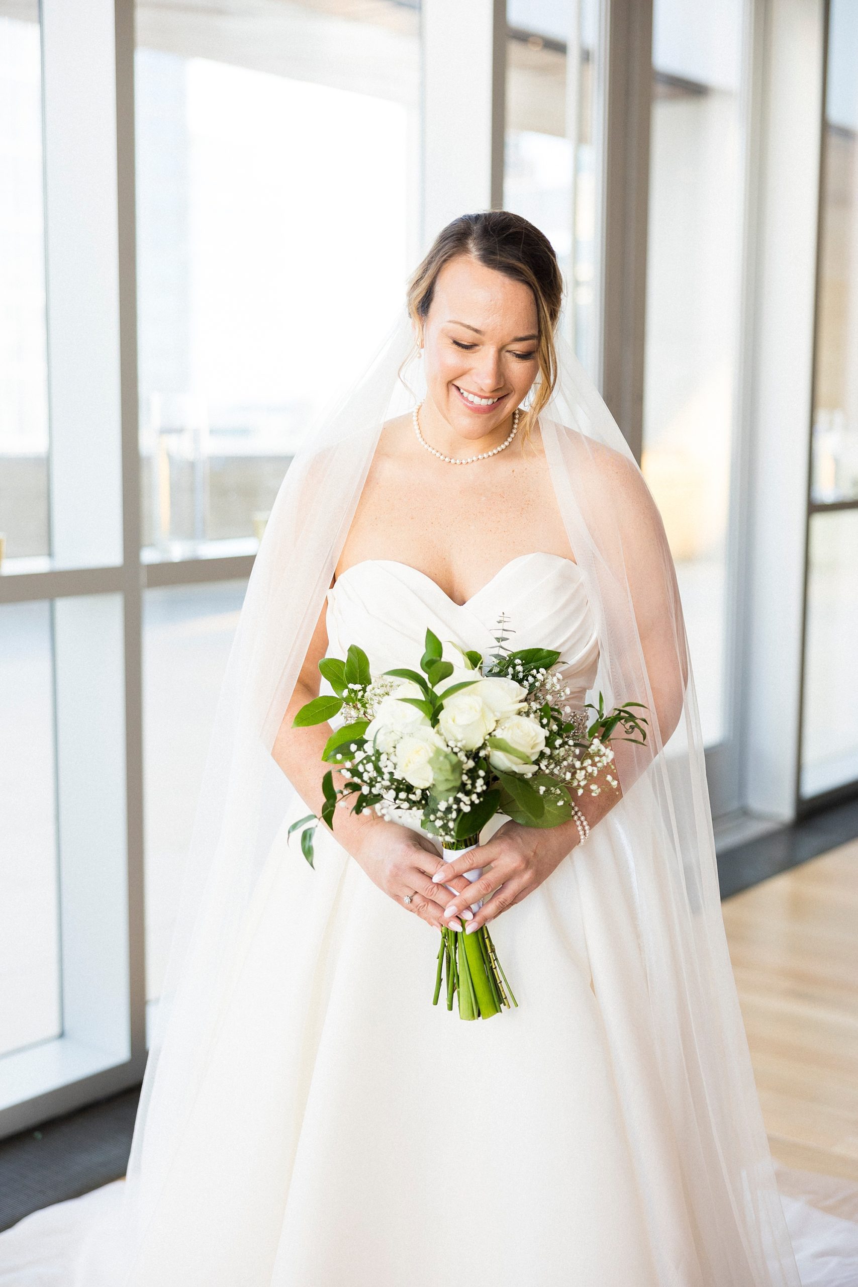 bride holds bouquet of white flowers before Mint Museum Uptown wedding