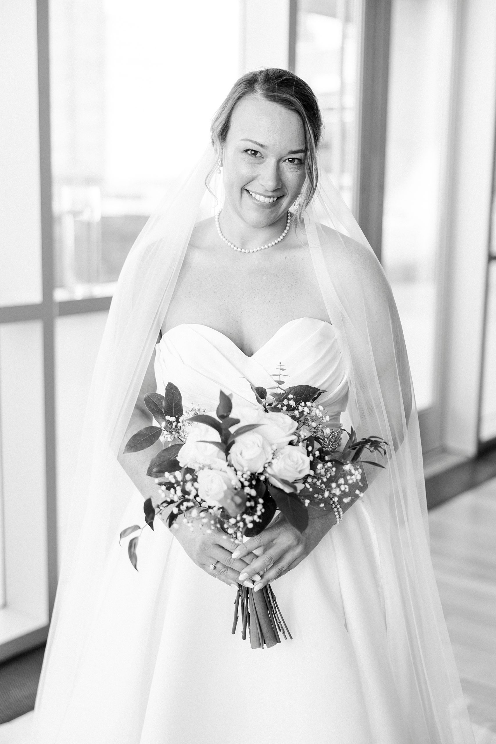 bride smiles holding bouquet of white flowers