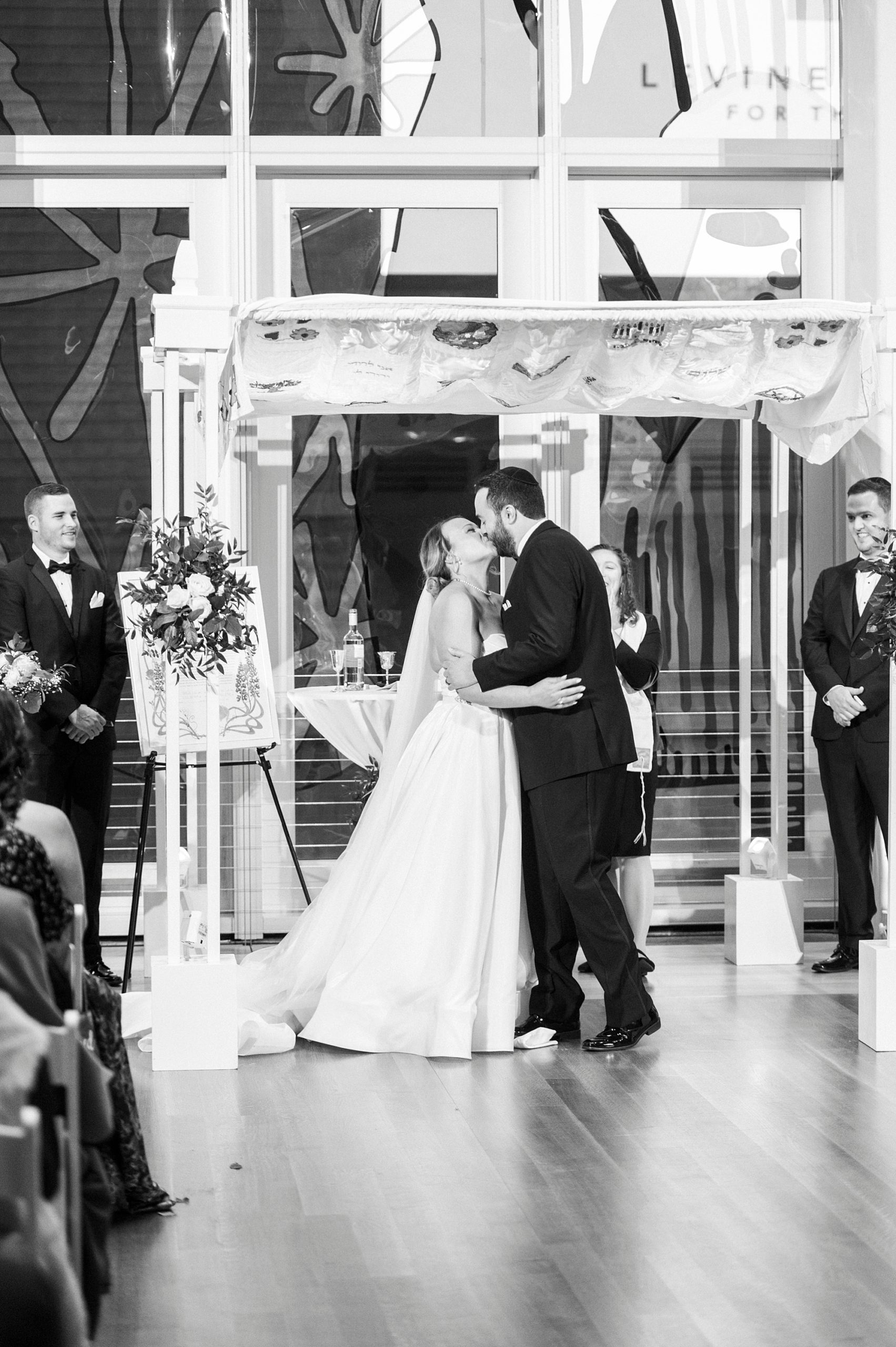 newlyweds kiss under canopy during Jewish wedding ceremony at Temple Beth El