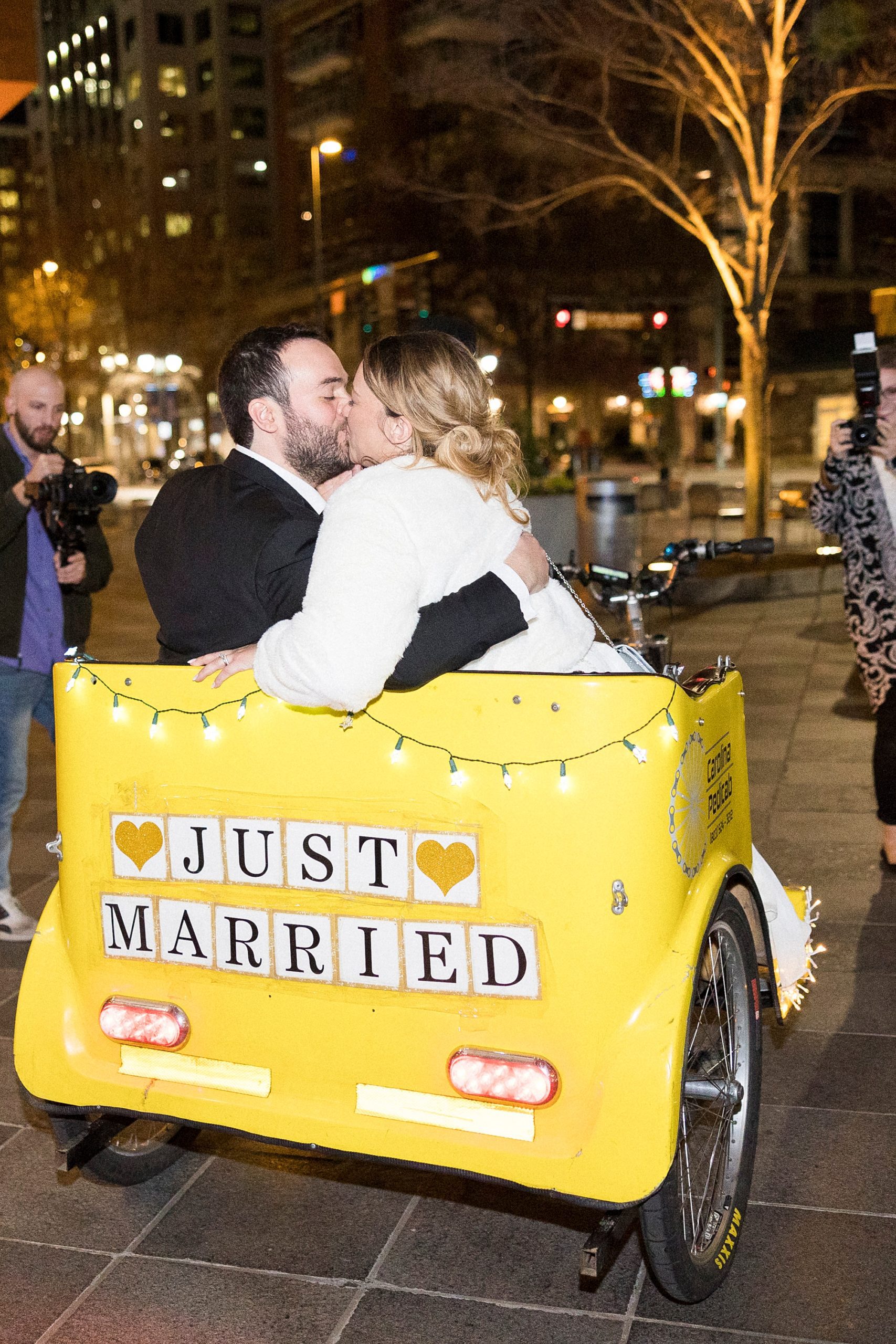 newlyweds kiss in pedi-cab during wedding getaway
