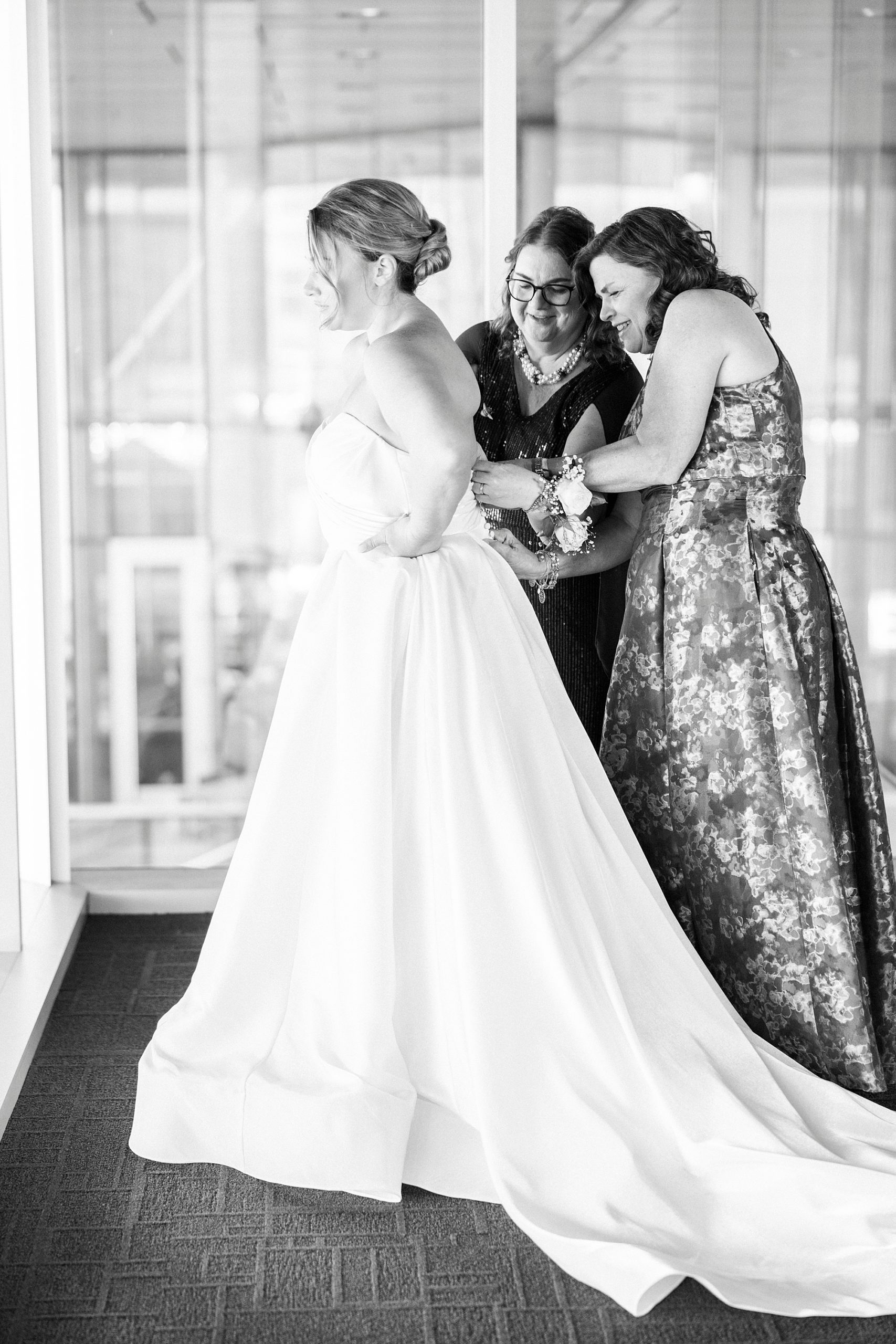 mom and sister help bride into wedding gown at the Mint Museum Uptown