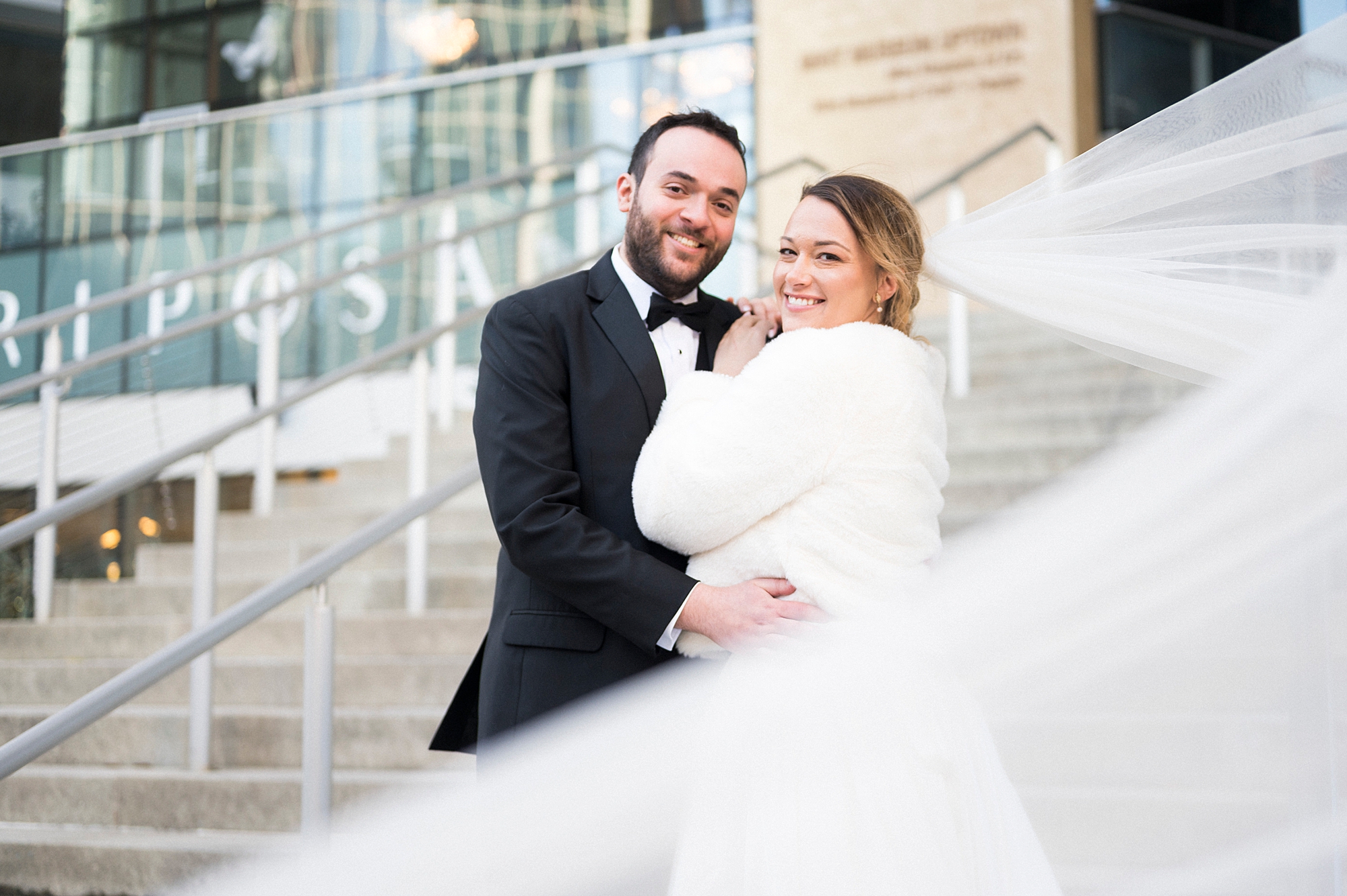 newlyweds hug on steps of the Mint Museum Uptown