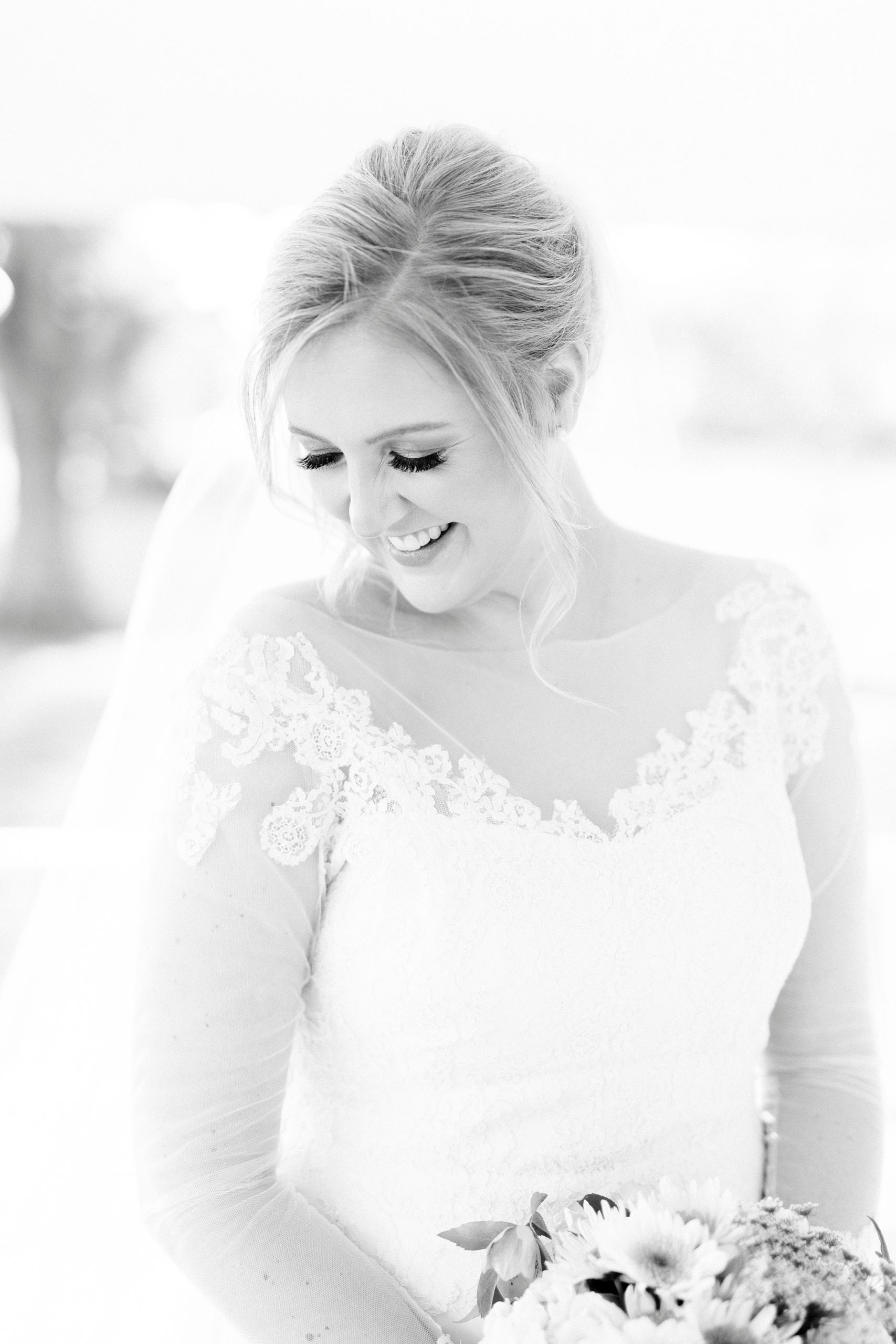 bride looks down smiling over shoulder in lace trimmed gown