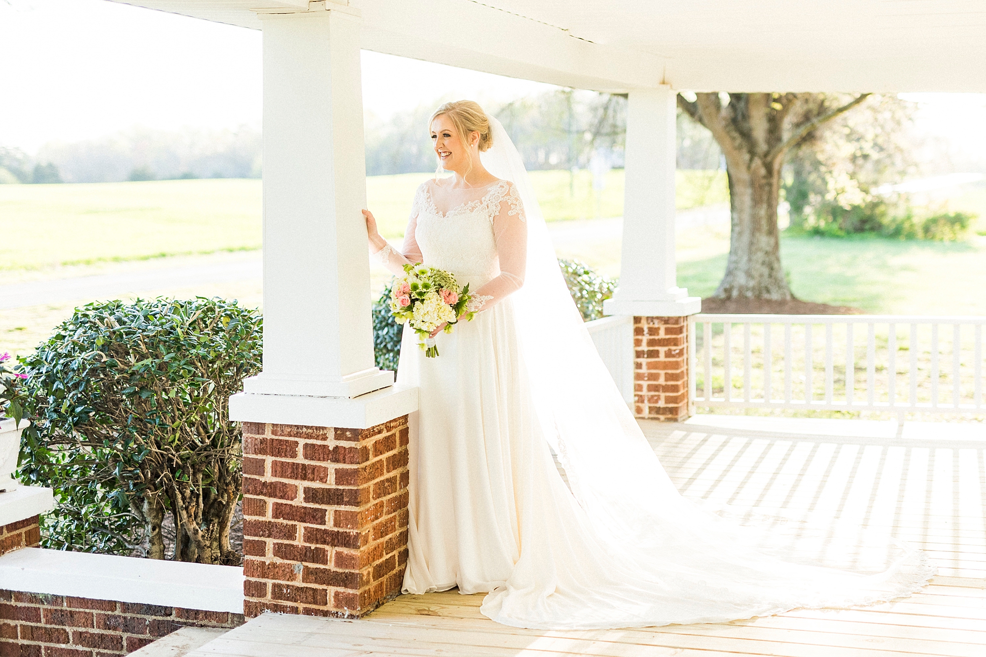 bride leans against pillar on front porch during Mooresville bridal portraits