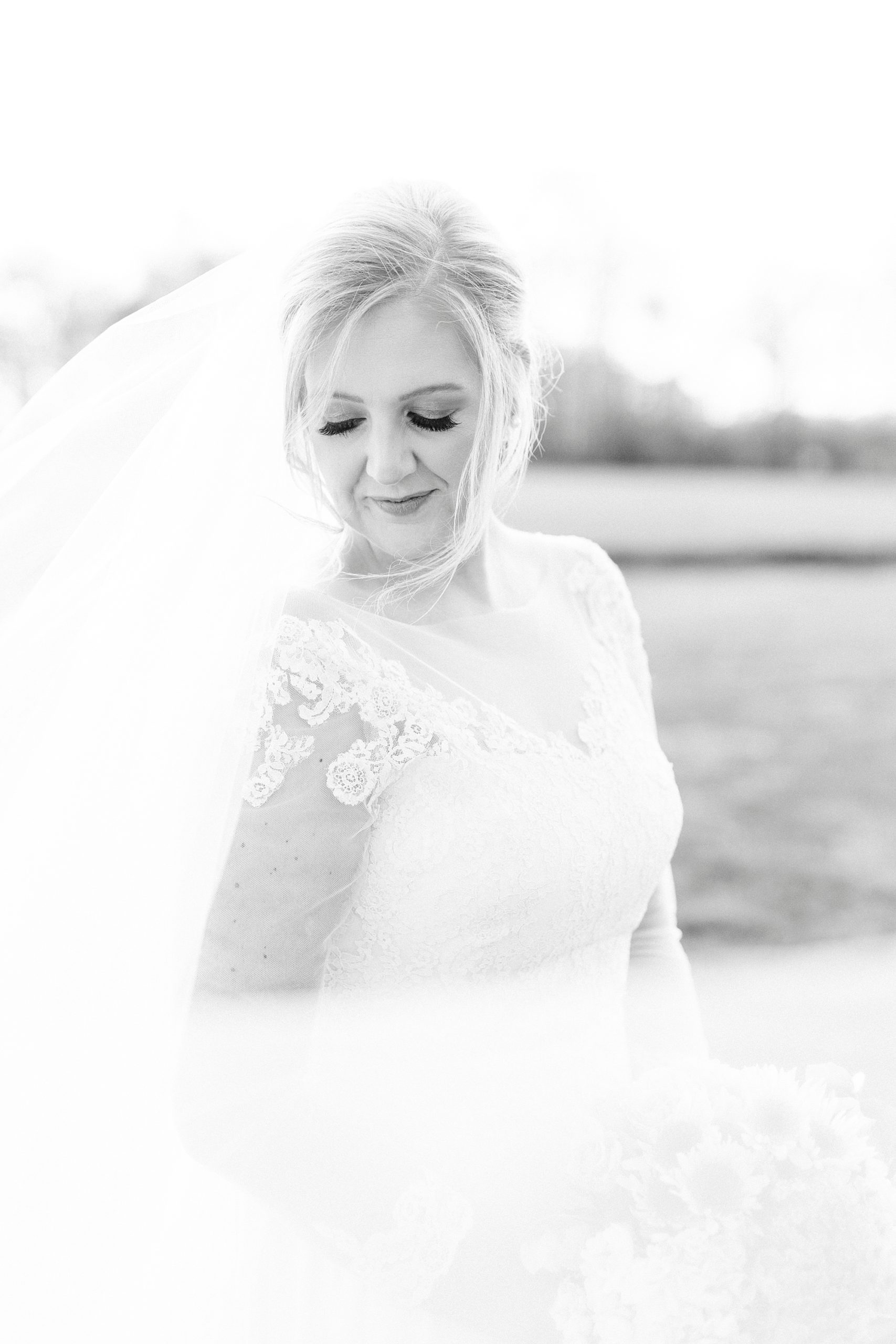 bride smiles over shoulder with veil around her