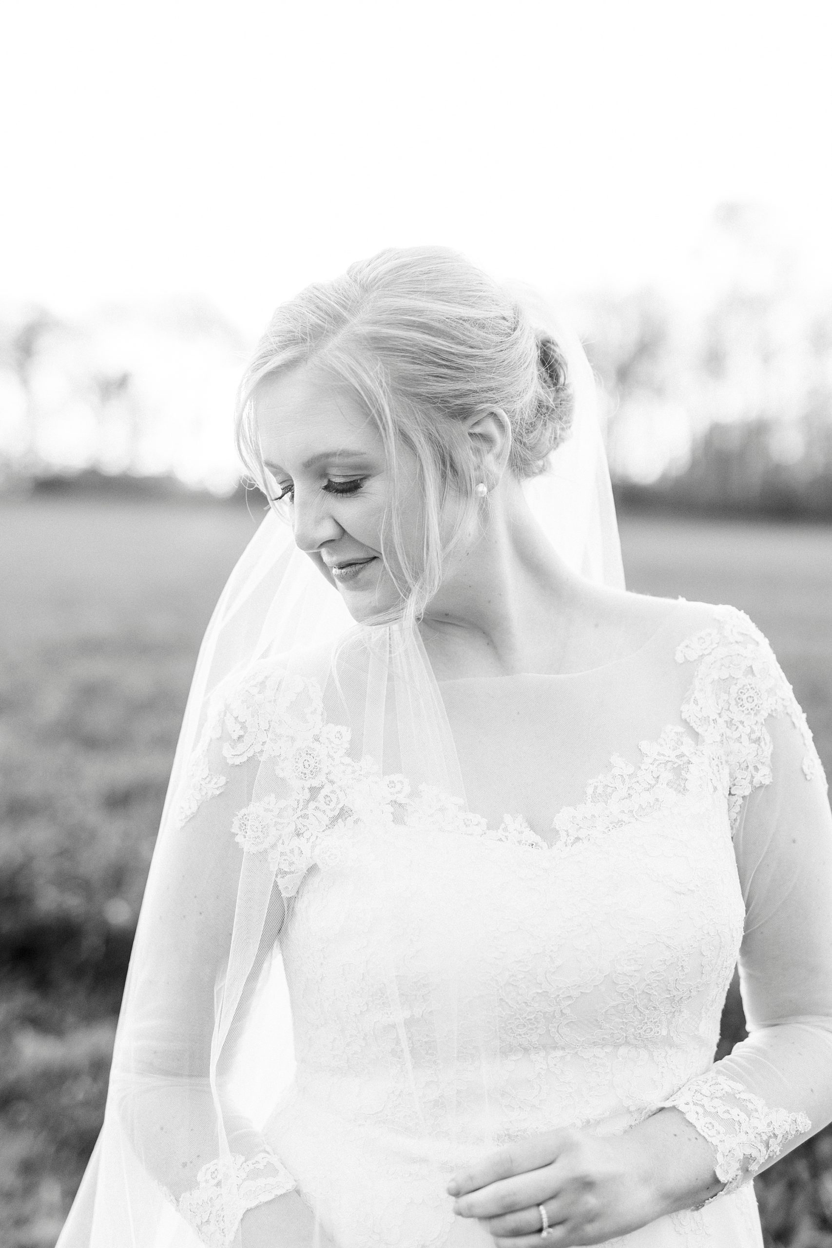 bride looks over shoulder with veil draped around custom wedding gown