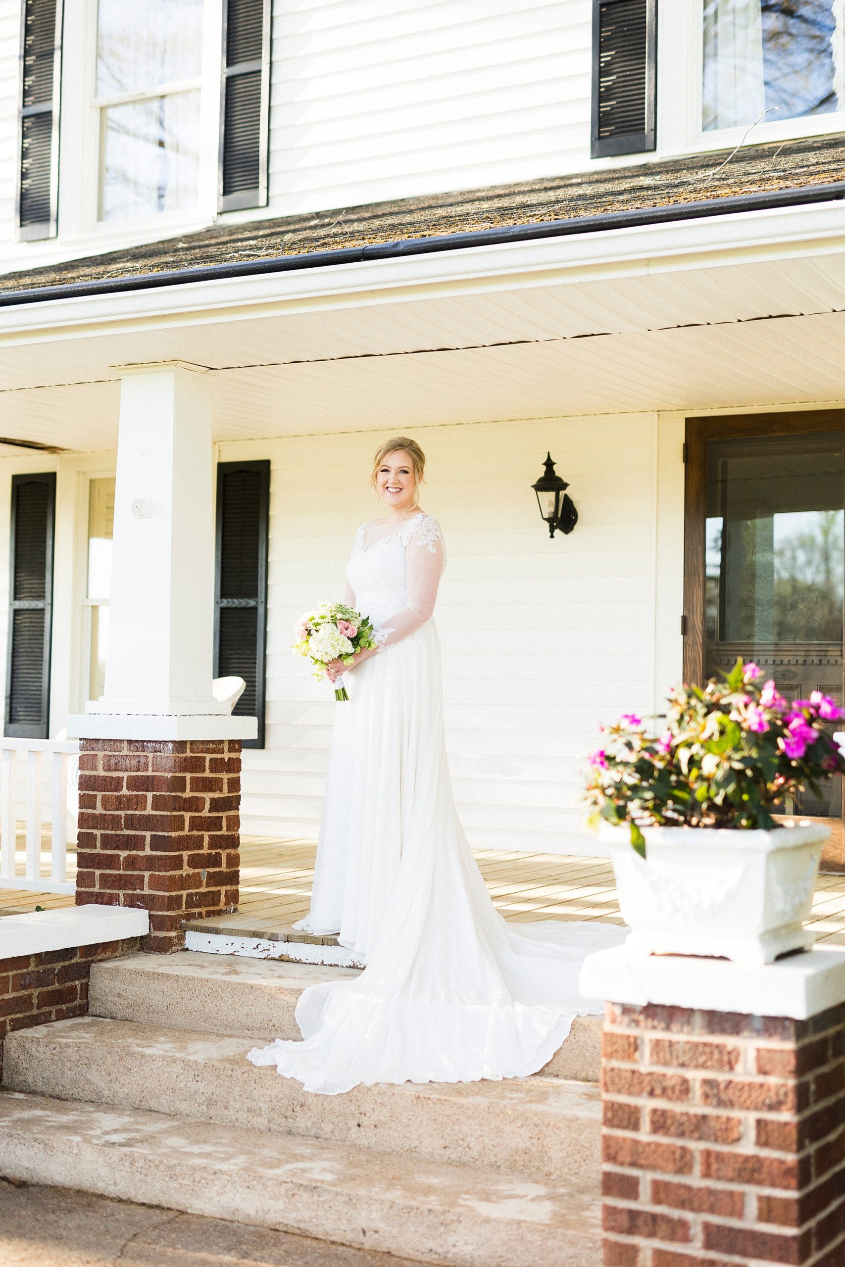 bride poses on steps at farmhouse during Mooresville bridal portraits