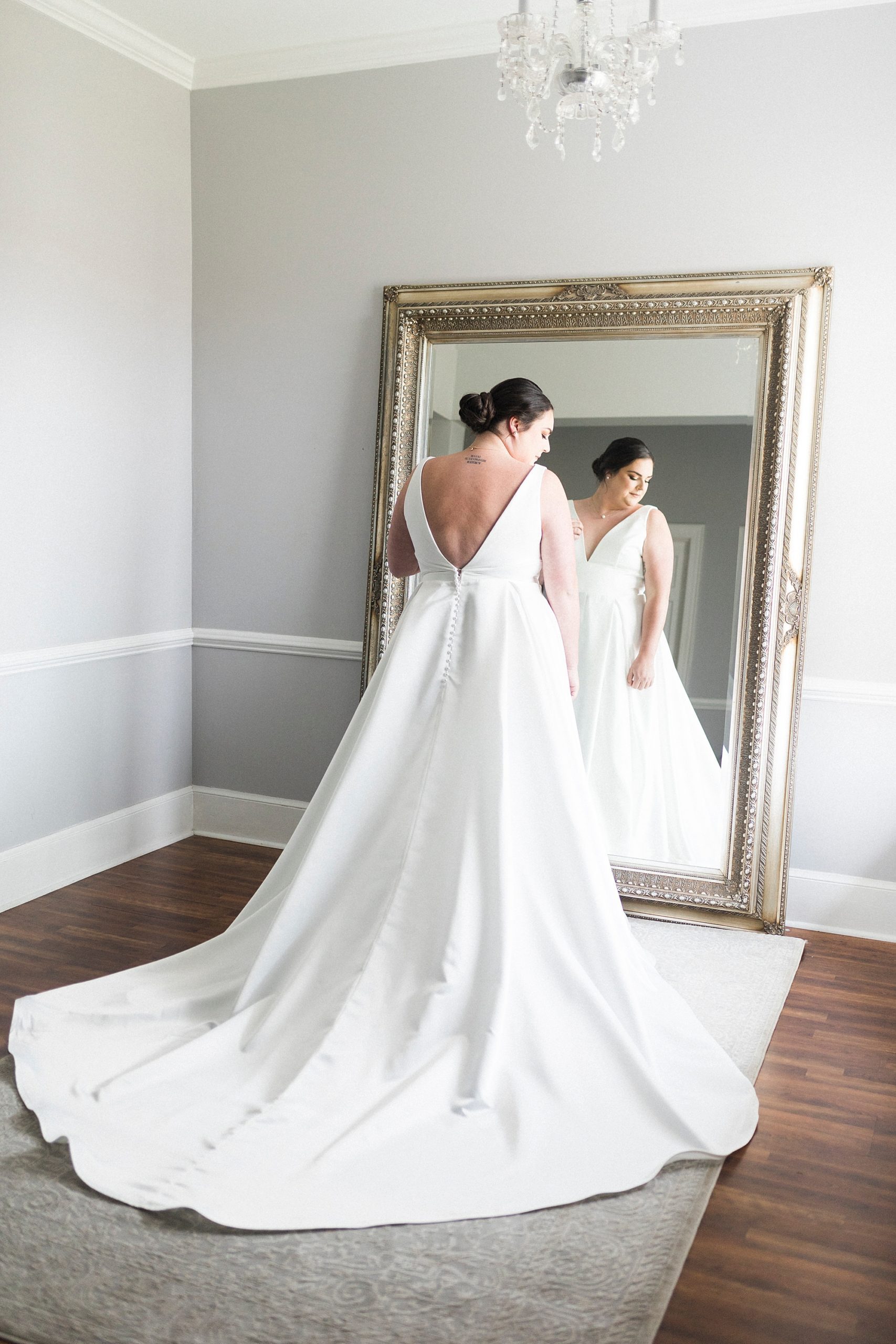 bride stands in wedding gown by floor length mirror at Separk Mansion