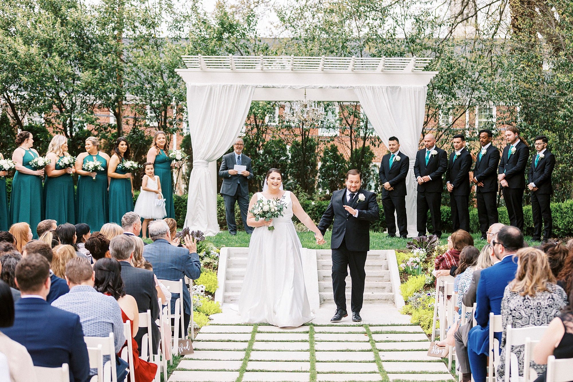 couple holds hands walking up aisle after outdoor ceremony at the Separk Mansion