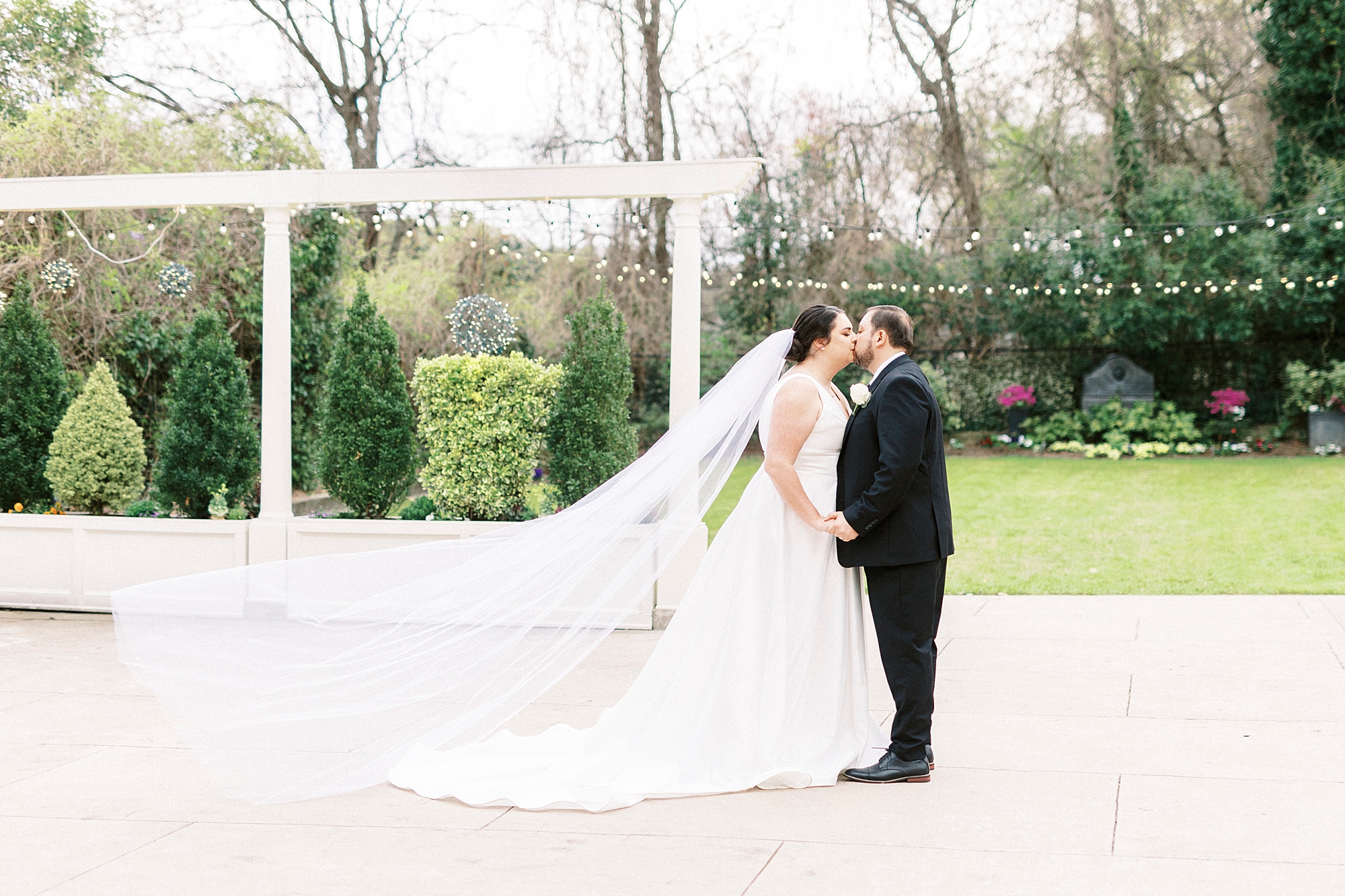 newlyweds hold hands while bride's veil floats behind them in garden at Separk Mansion