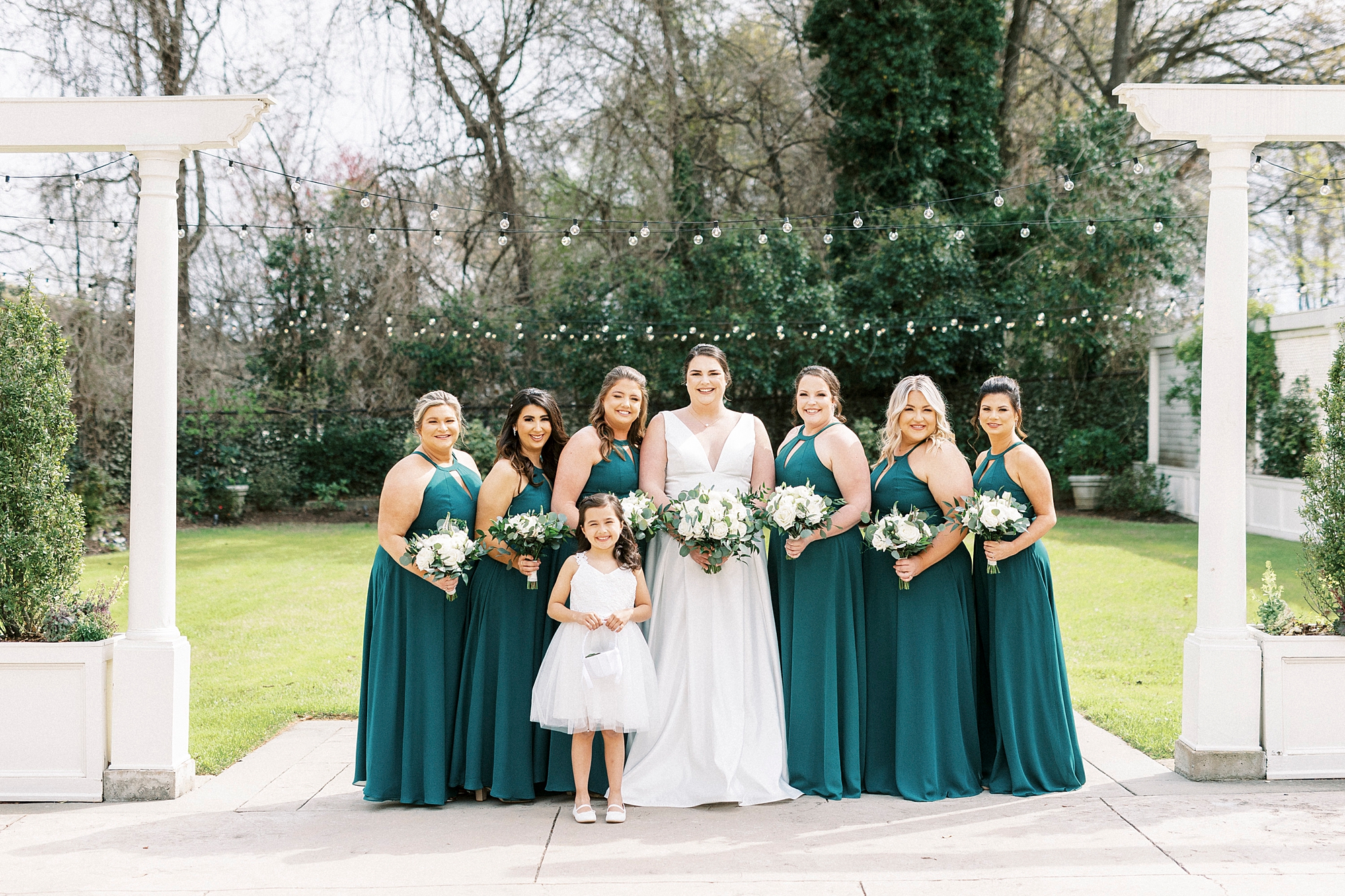 bride and bridesmaids in emerald green pose under twinkling lights at Separk Mansion