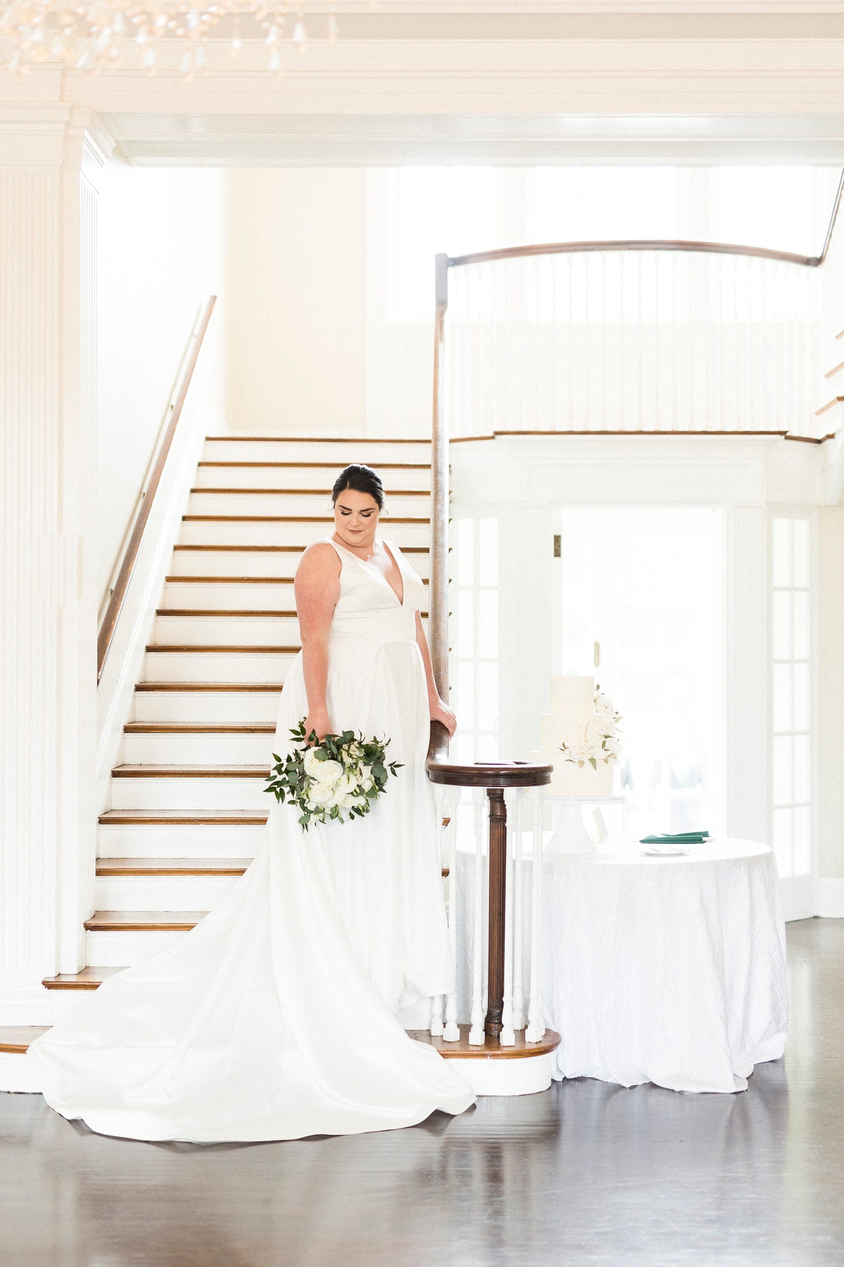 bride stands on staircase at Separk Mansion with wedding gown draped around steps