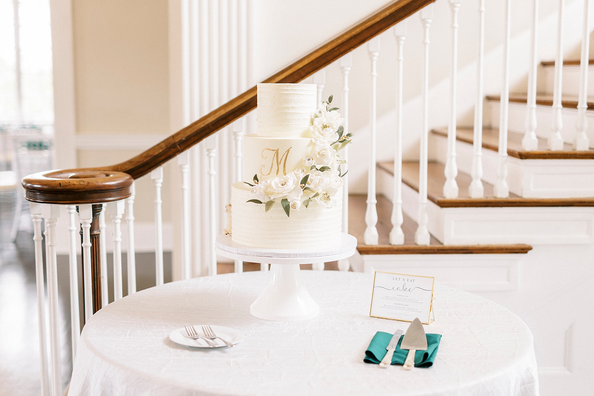 tiered wedding cake sits on table by staircase at Separk Mansion