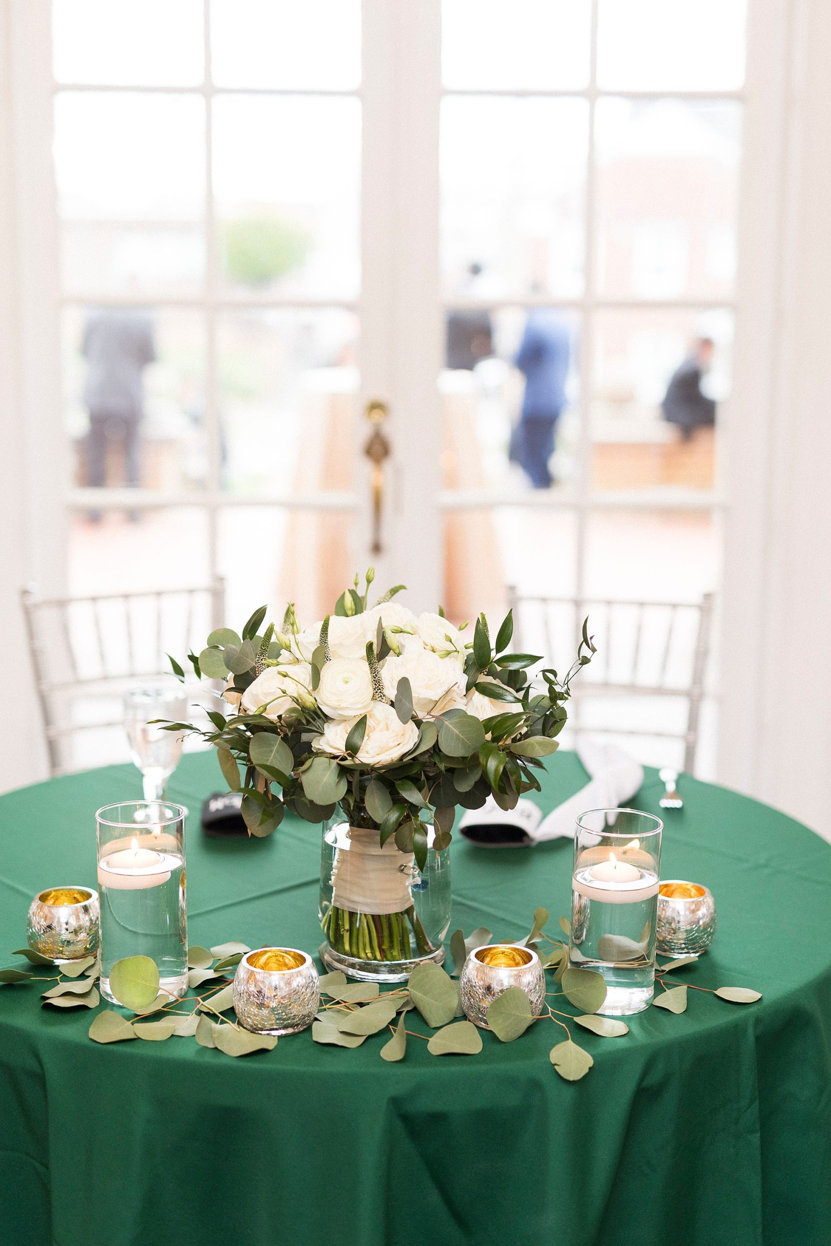 reception table with green tablecloth and bride's bouquet 