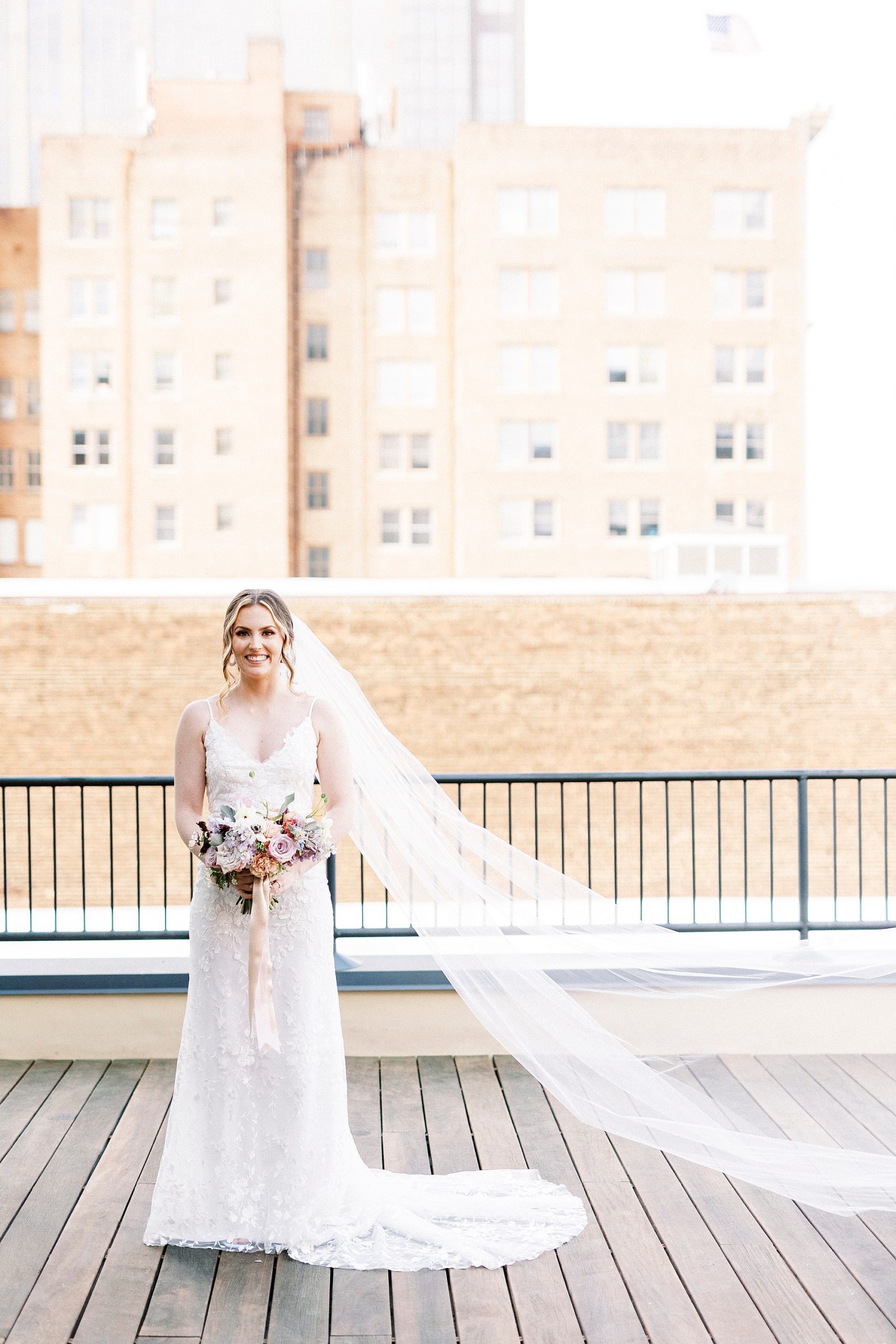 bride stands on patio at the Stockroom at 230 with veil floating