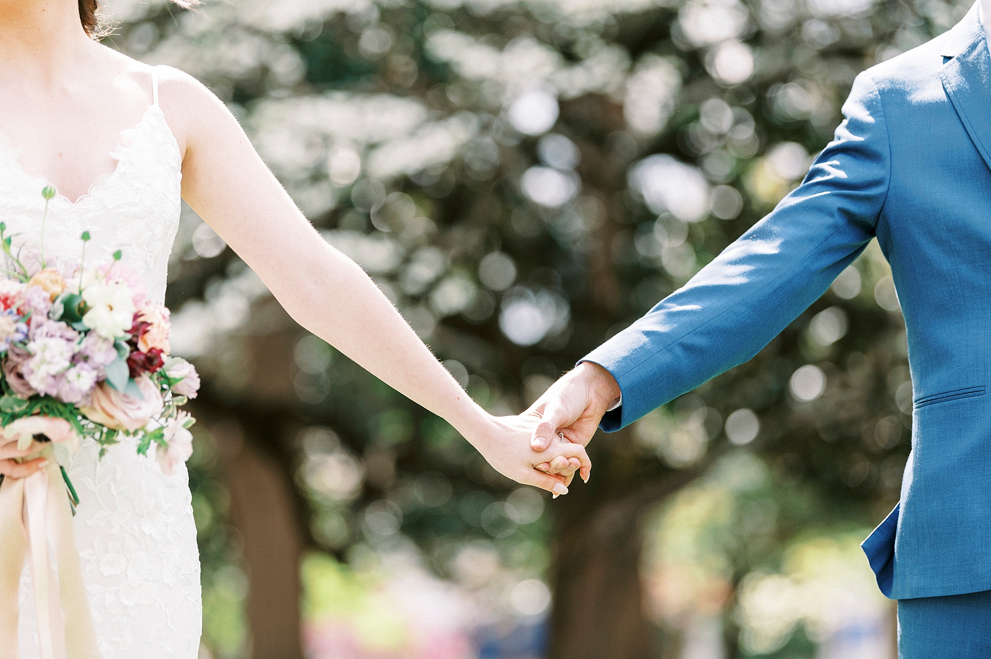 couple holds hands walking in courtyard during spring wedding