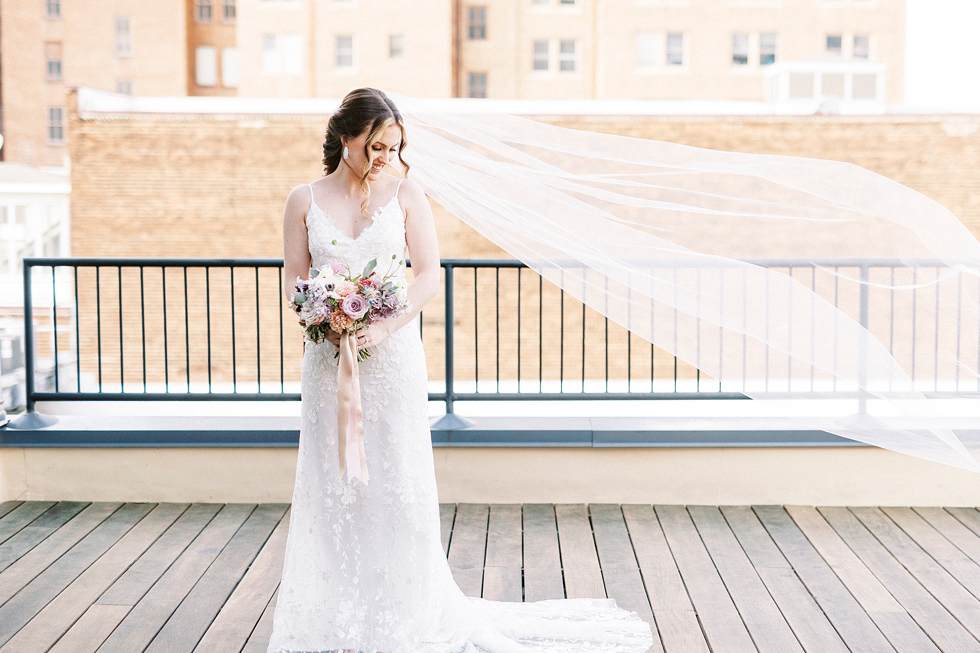 bride stands on patio with veil floating at Stockroom at 230