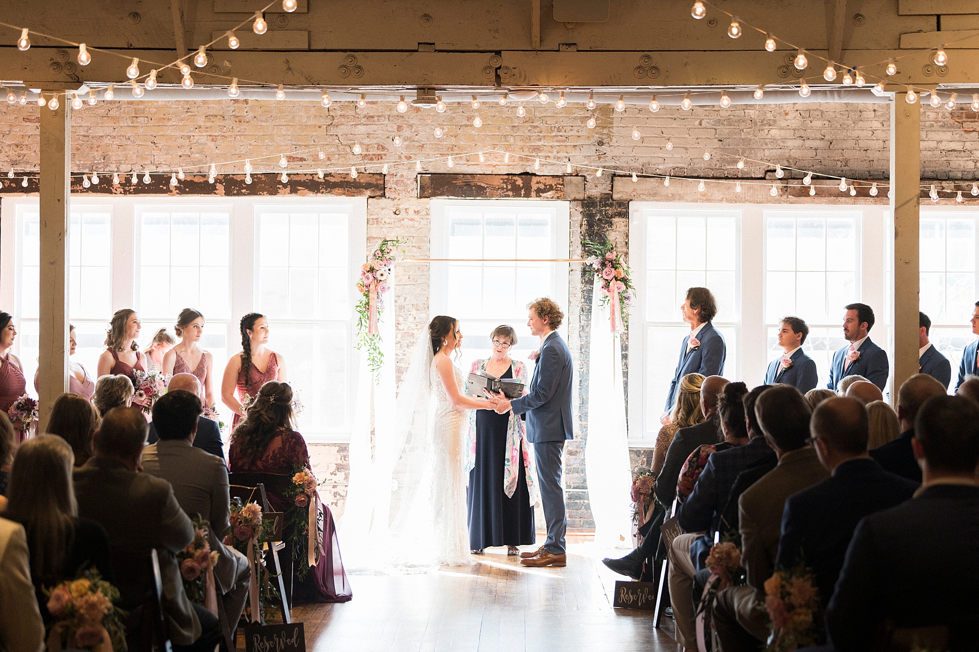 bride and groom hold hands during ceremony at the Stockroom at 230