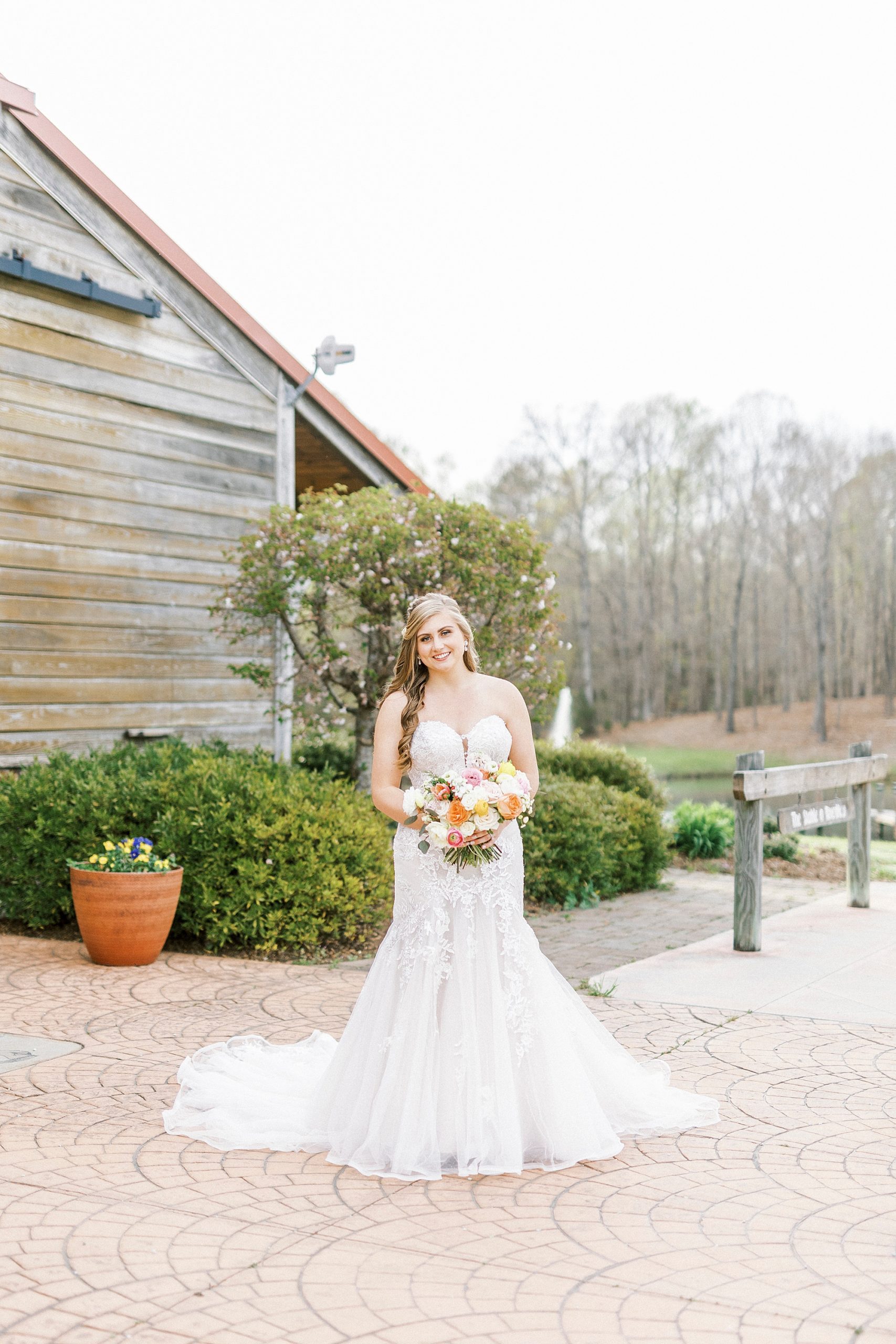 bride smiles by wooden barn at The Stable at Riverview
