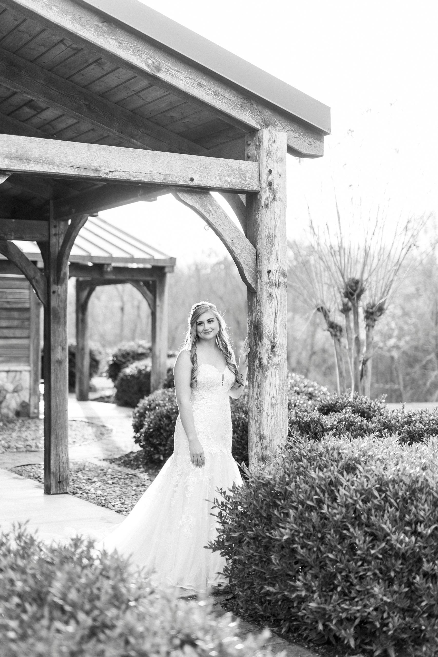 bride leans on wooden pillar at The Stable at Riverview