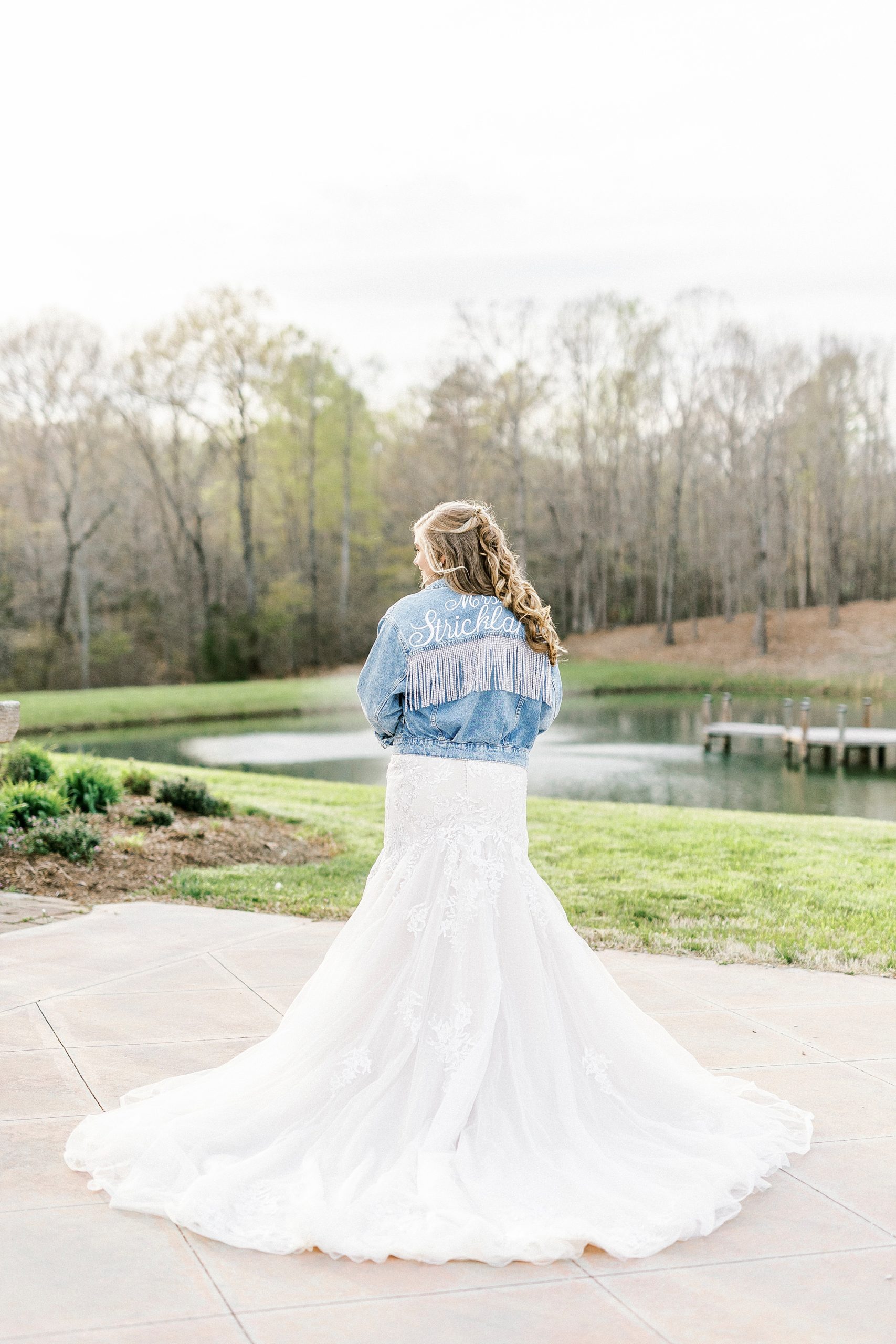 bride poses in custom jean jacket during The Stable at Riverview bridal portraits 
