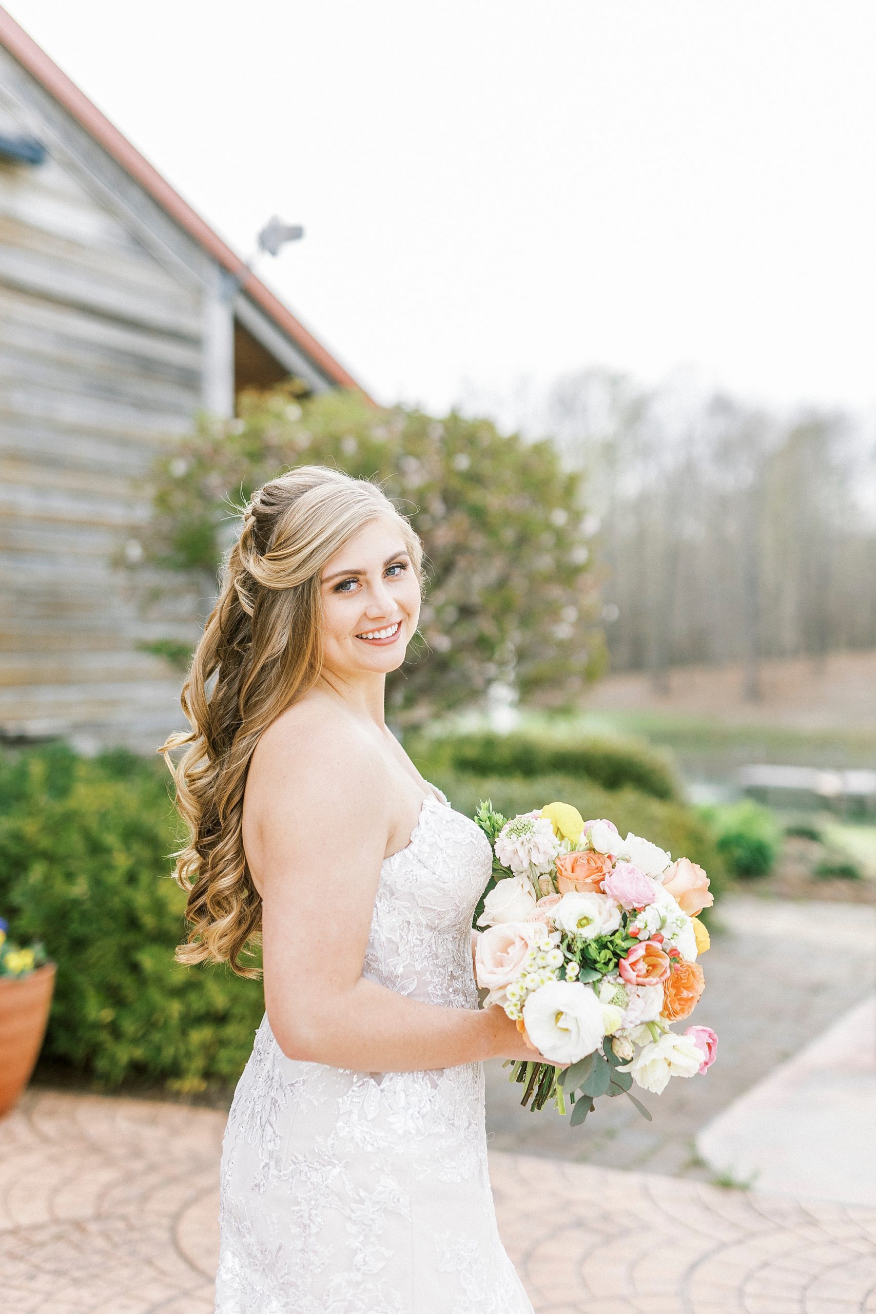 bride smiles holding colorful bouquet during The Stable at Riverview bridal portraits