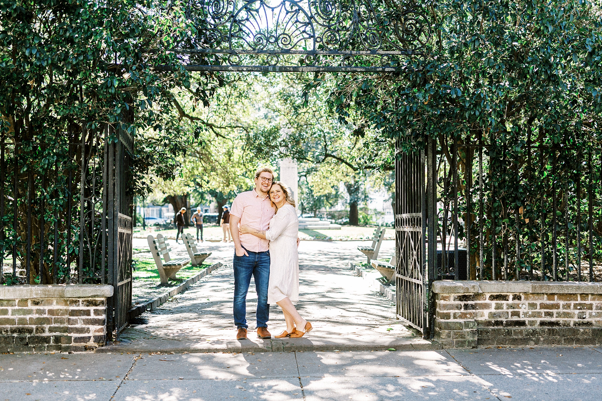 husband and wife pose under gate in downtown Charleston