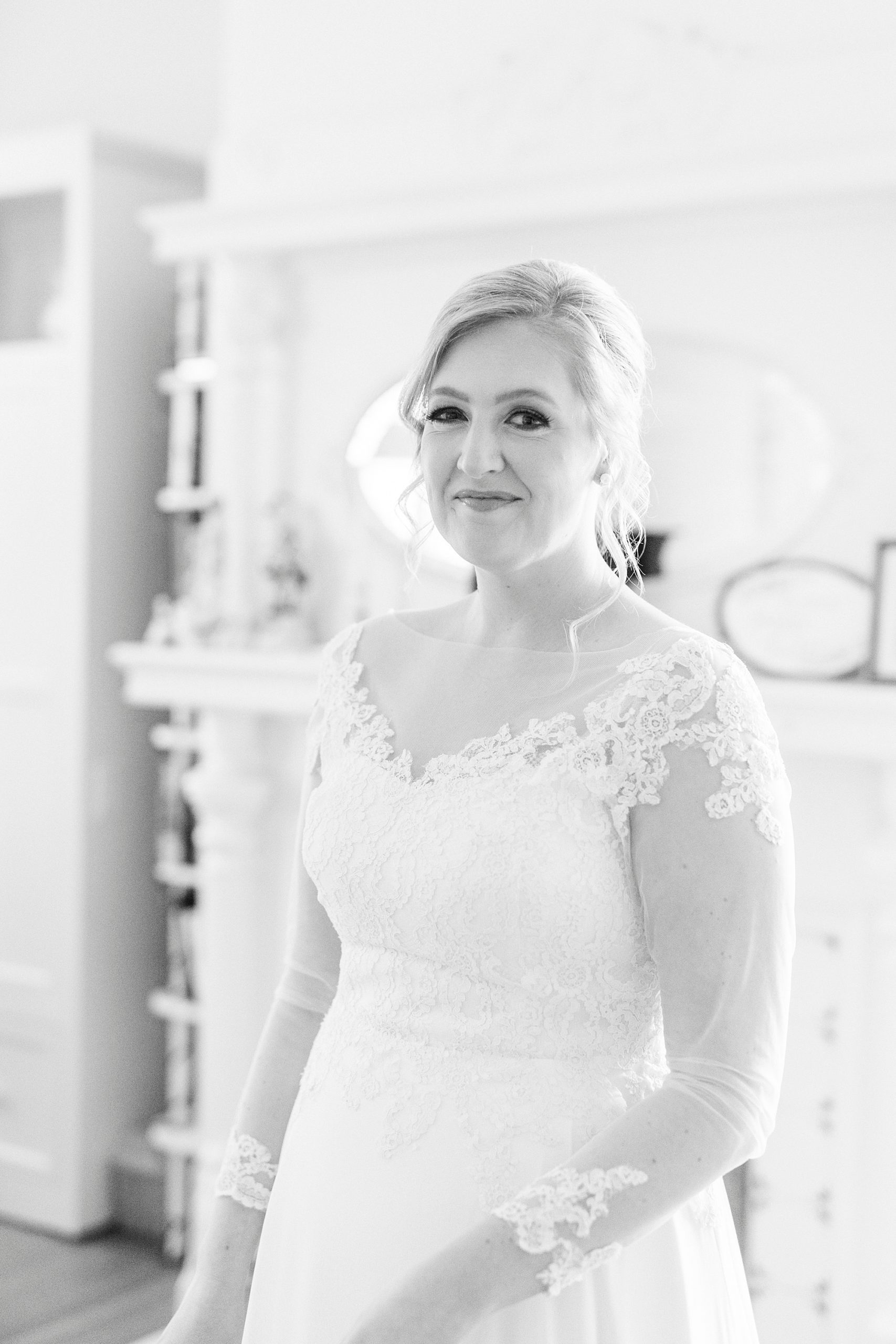 bride smiles in lace sleeved wedding gown