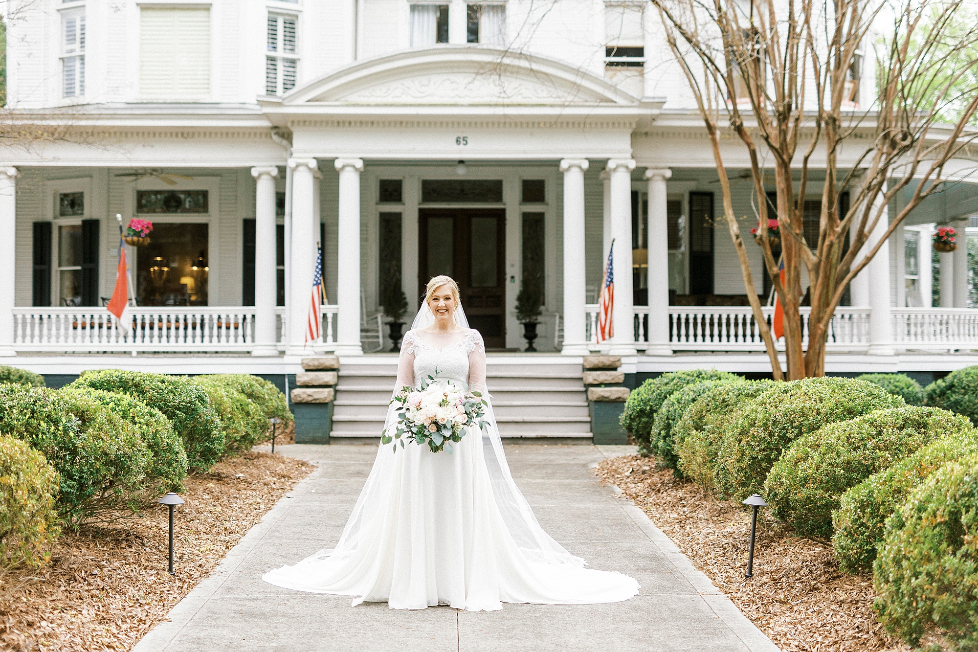 bride stands outside historic home on wedding day
