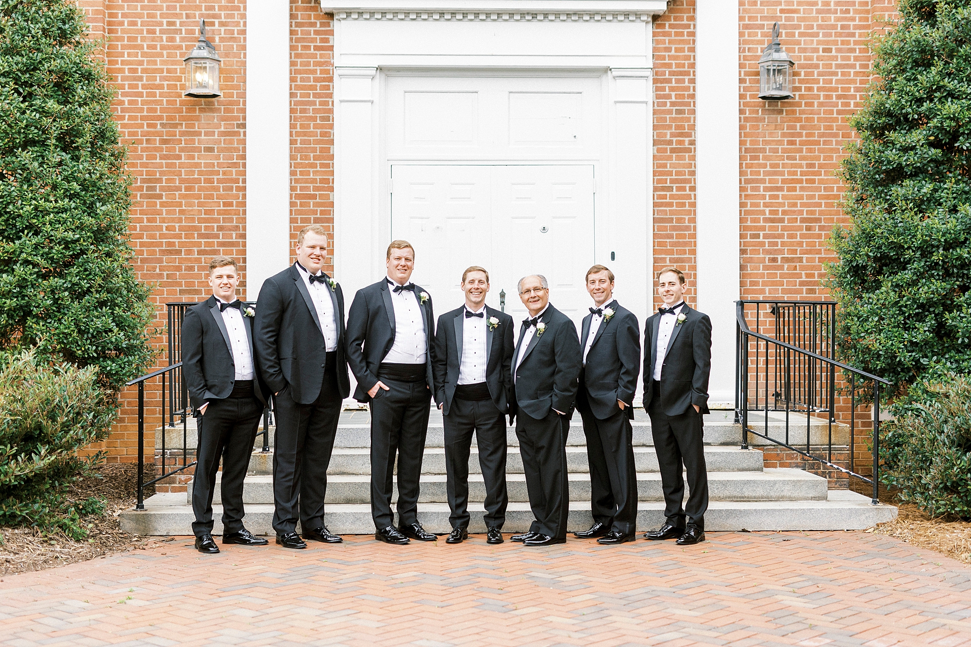 groom and groomsmen stand in suits before NC wedding