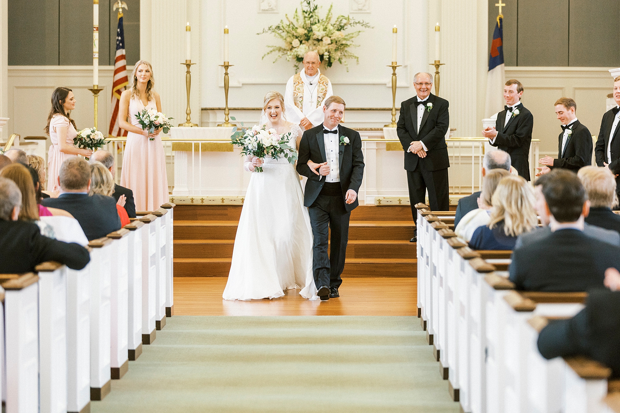 newlyweds walk up the aisle after traditional church wedding in Concord NC