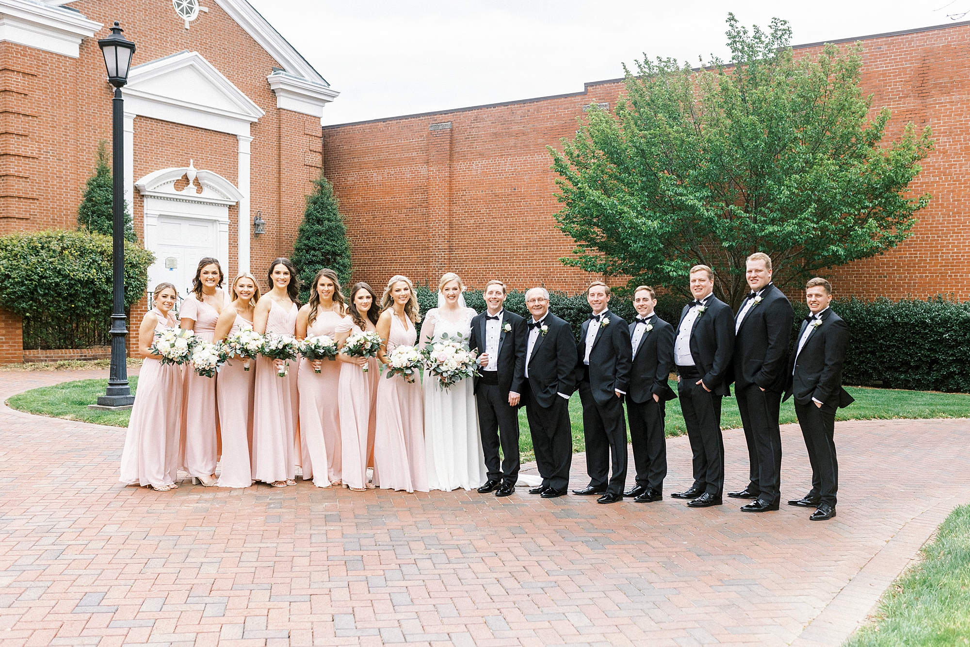 bride and groom stand with wedding party