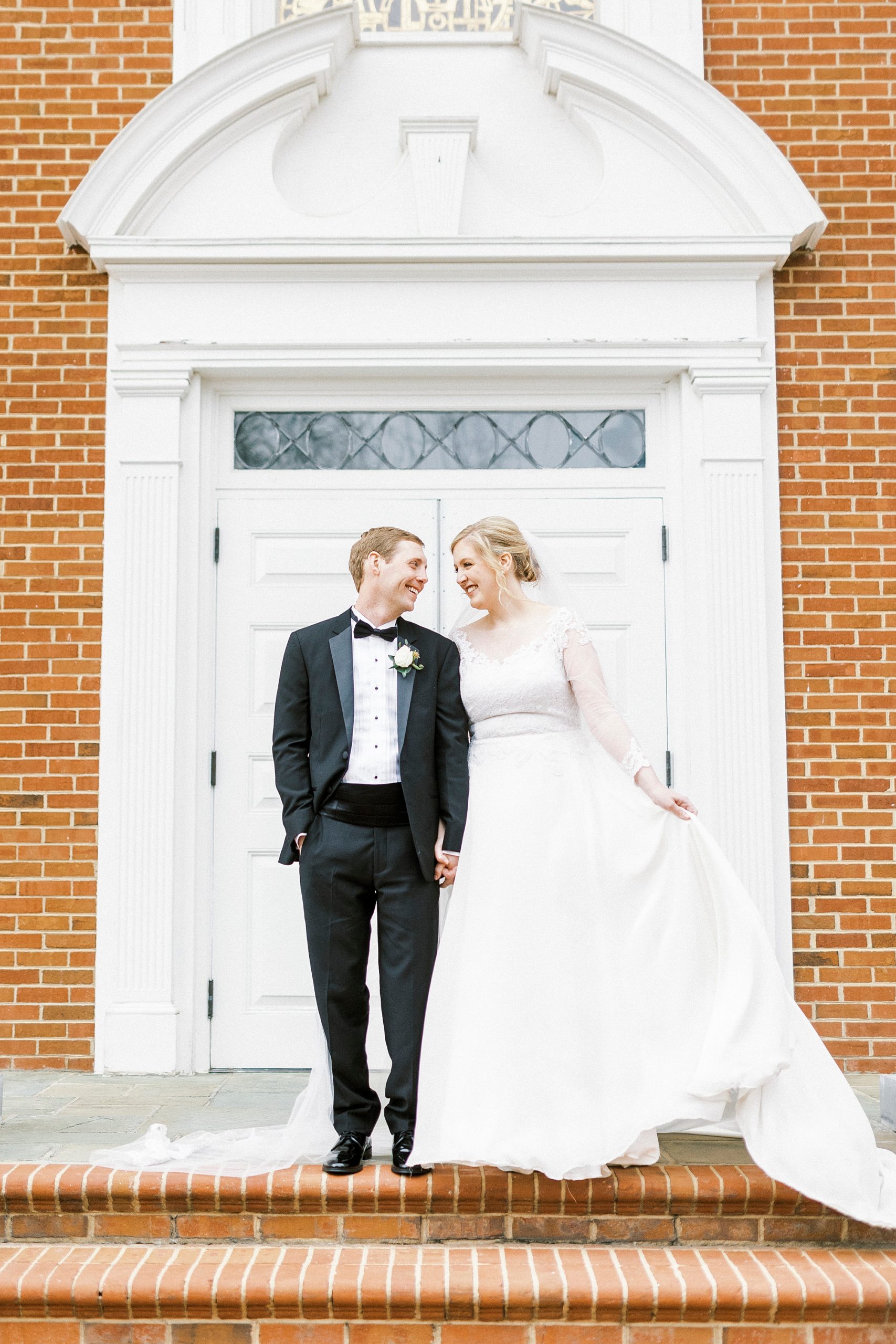 bride and groom stand on stairs at church 