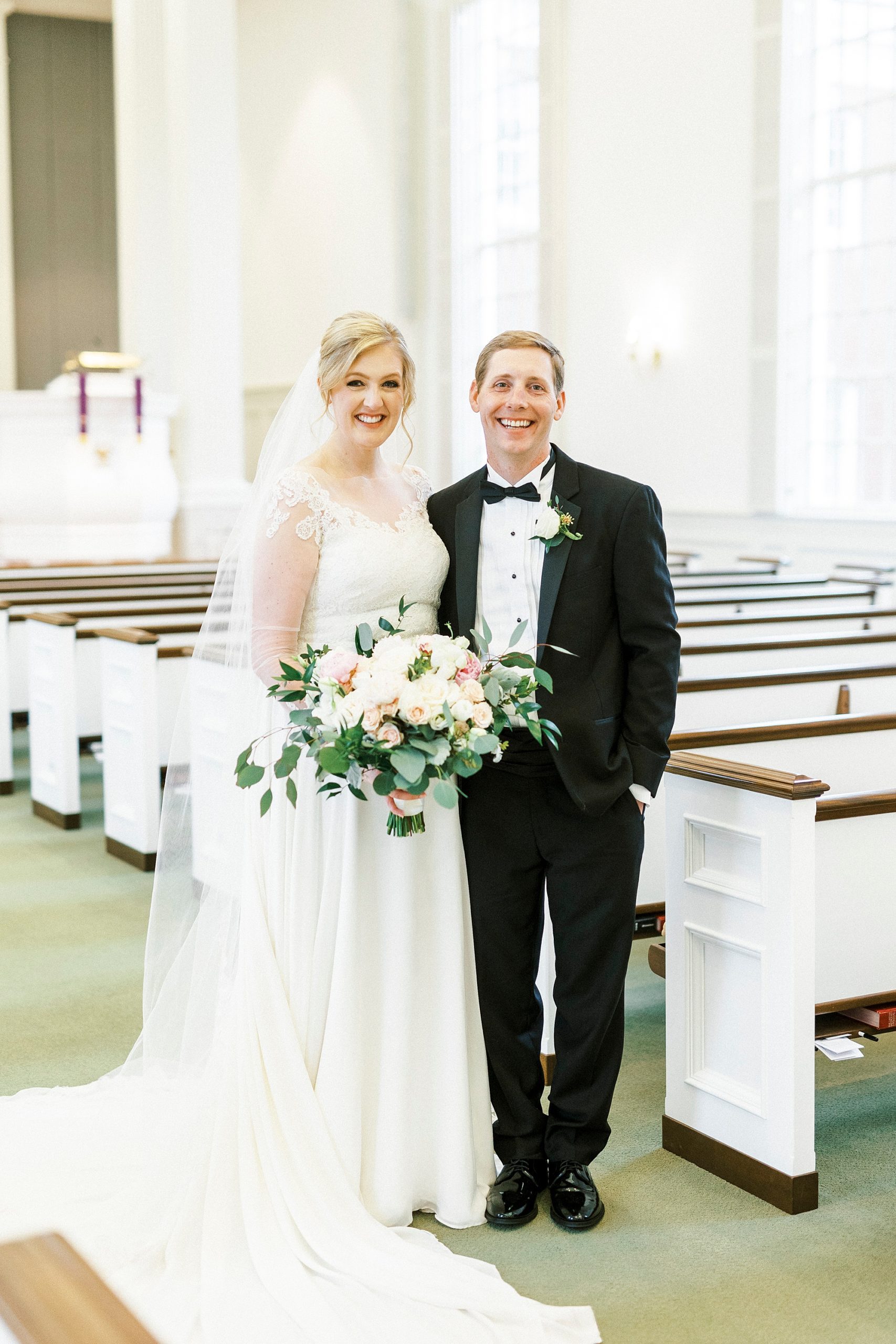 bride and groom stand by pews in church