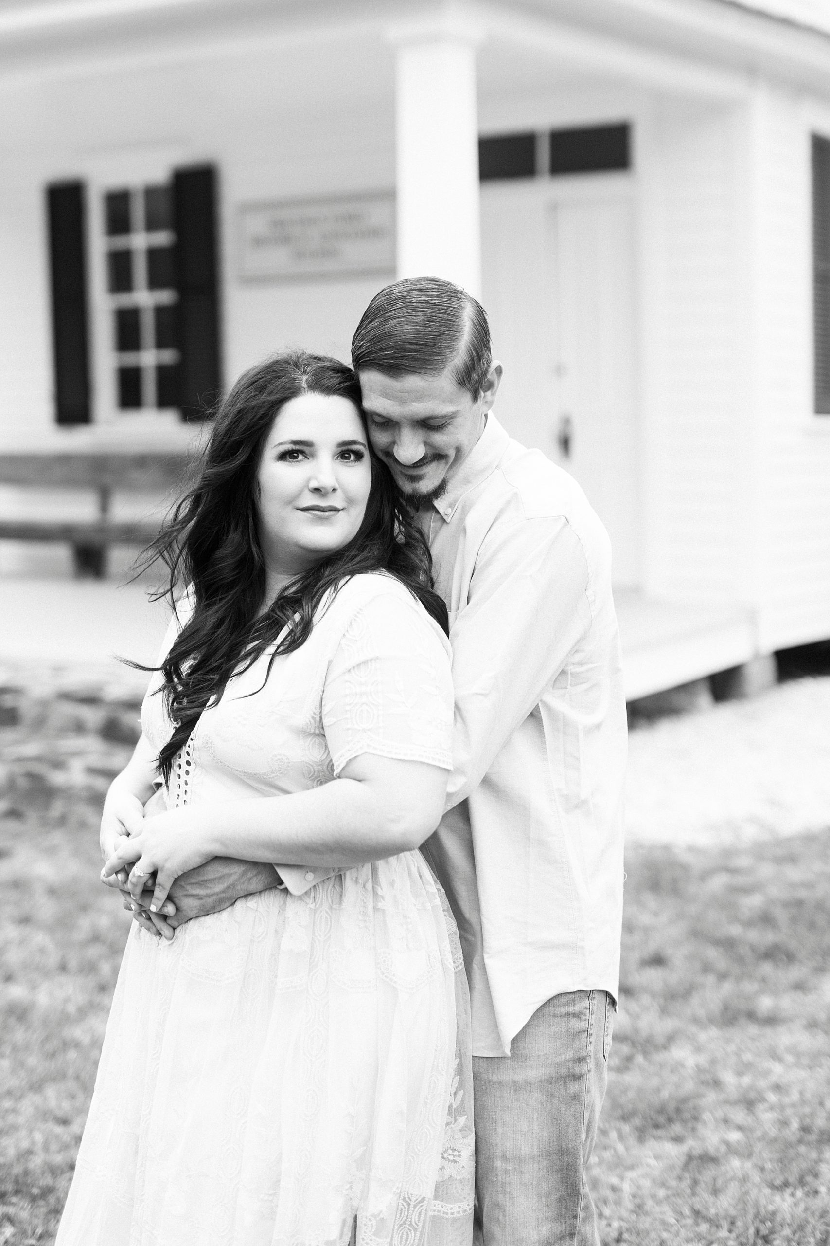 groom hugs bride from behind during white chapel engagement session