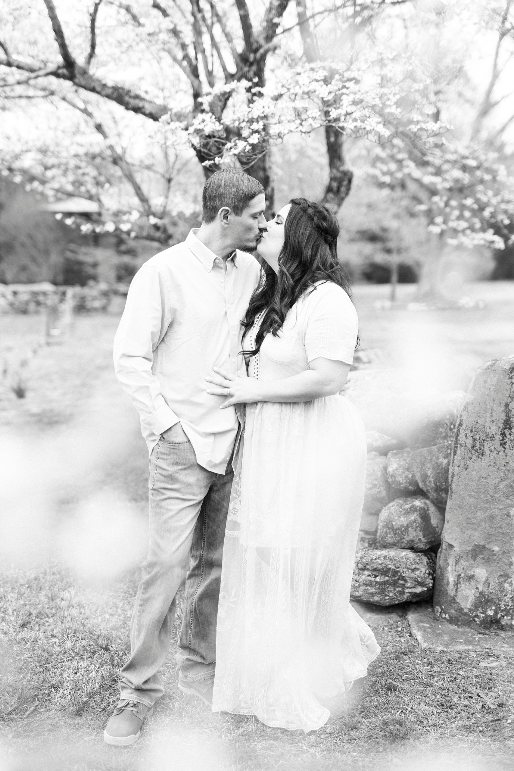 couple kisses in front of stone wall during white chapel engagement session