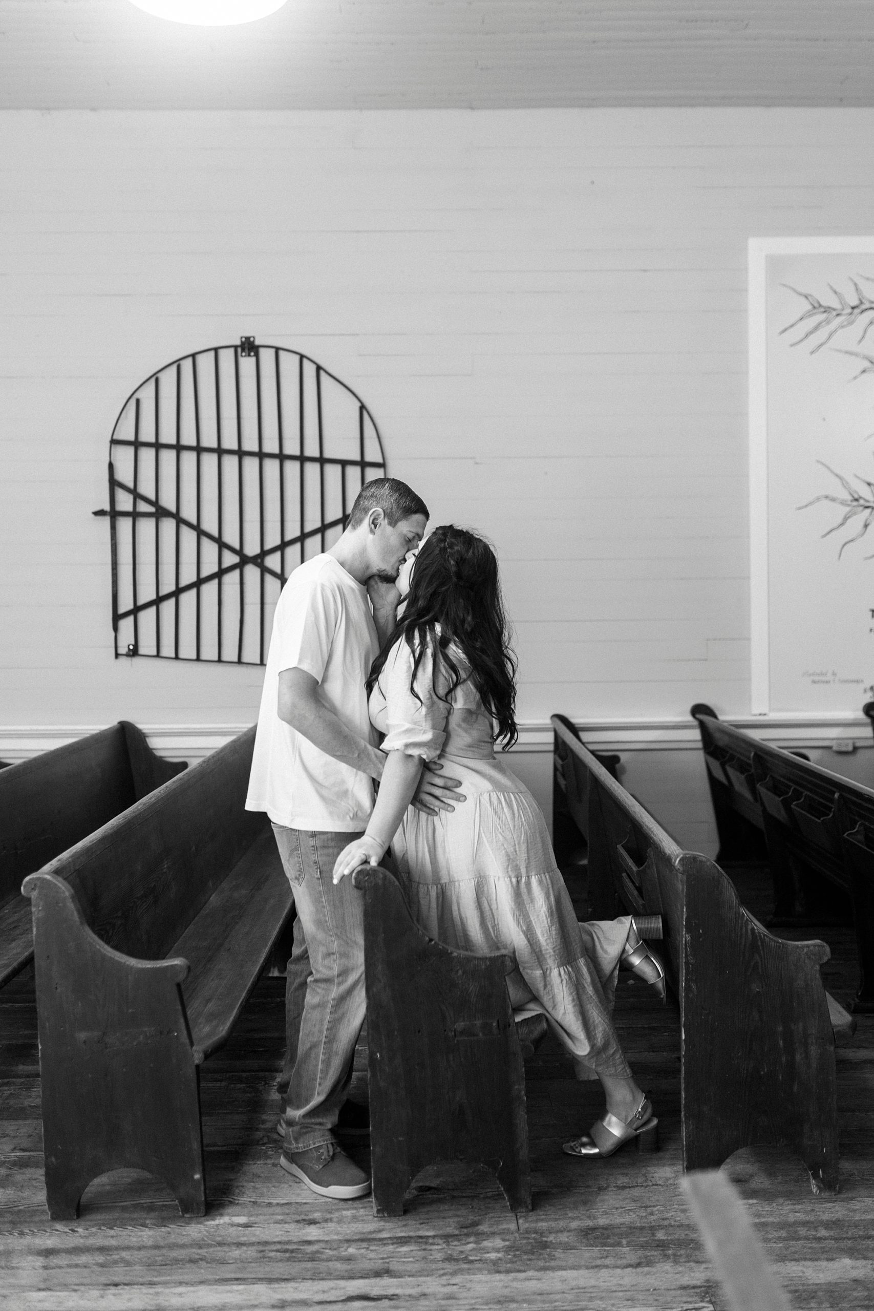 couple kisses inside chapel on wooden pews