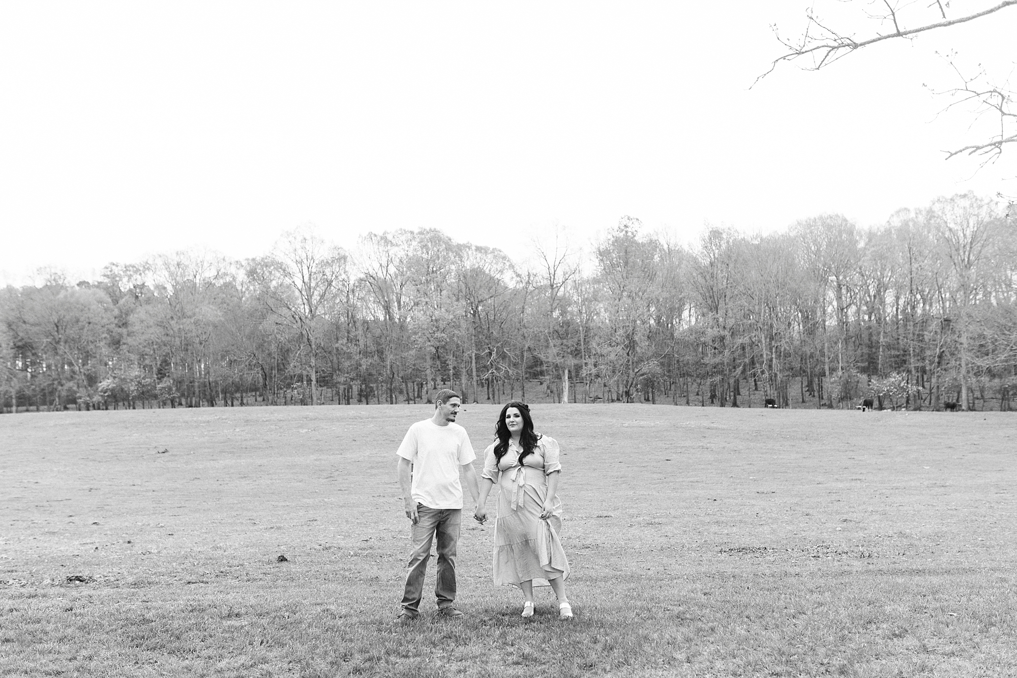 couple stands in open field holding hands