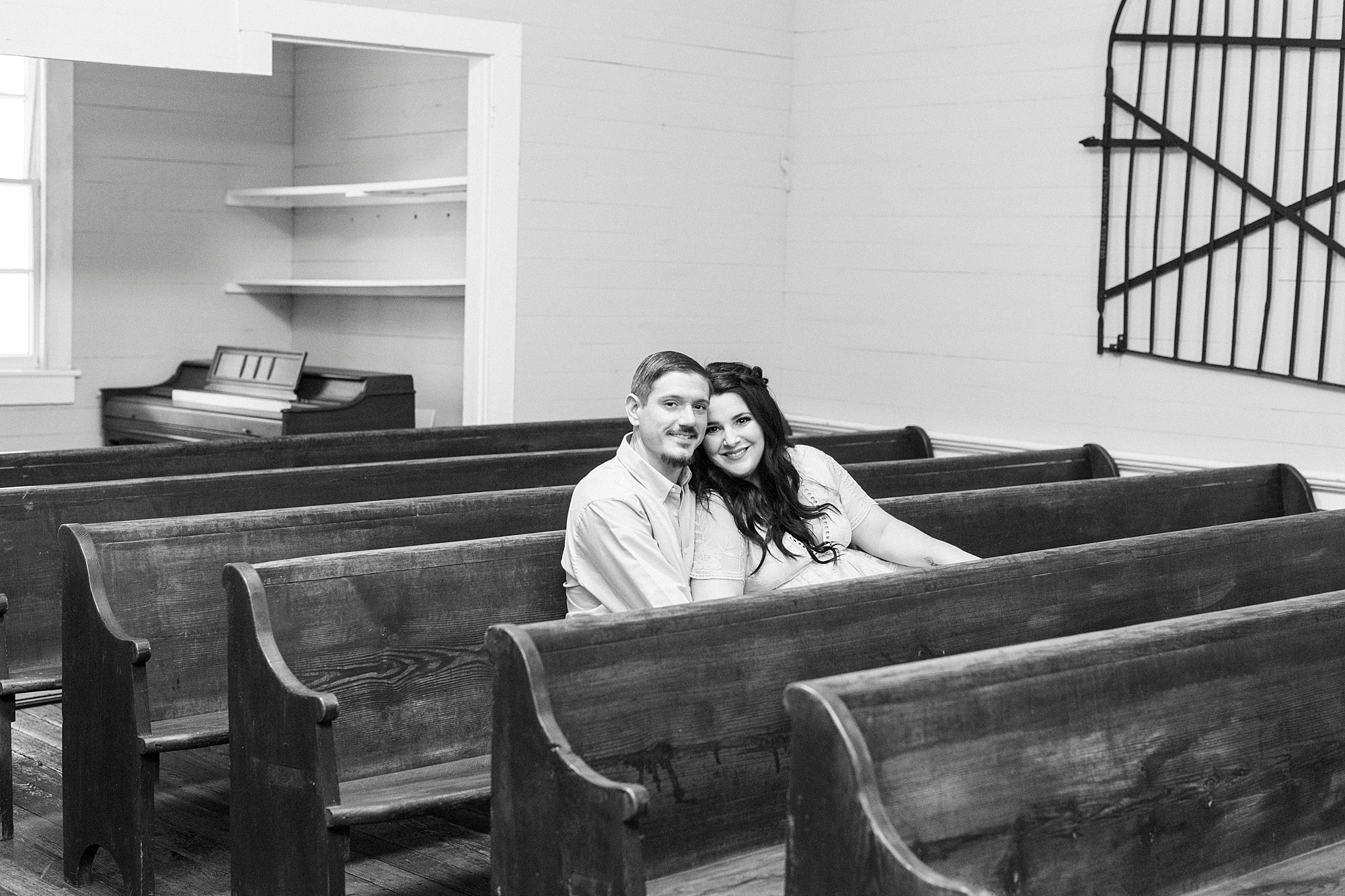 engaged couple sits on wooden pews in family chapel